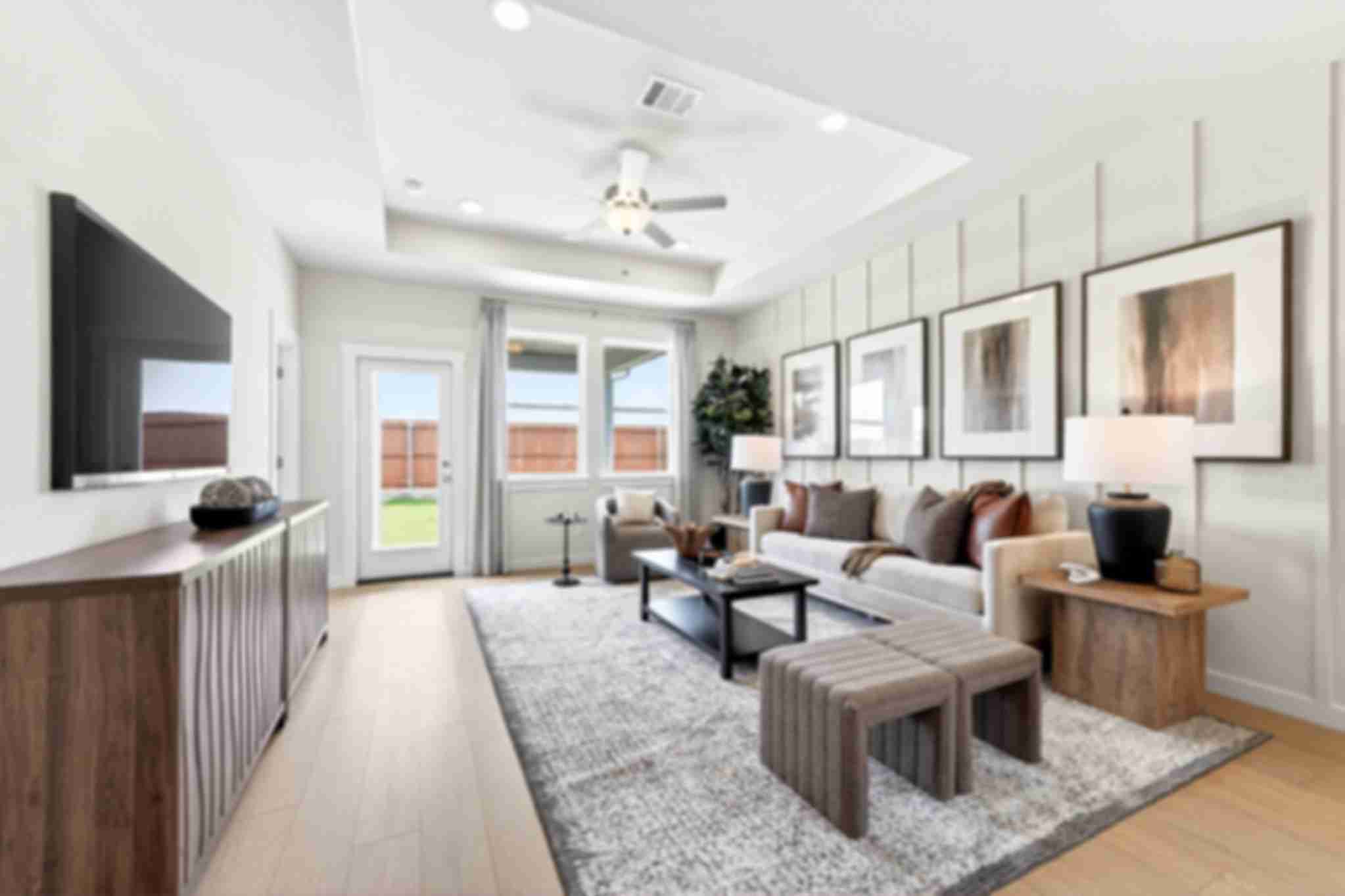 Modern living room in Mesa Vista, San Antonio by Davidson Homes, featuring a tray ceiling, board and batten wall, and decor.