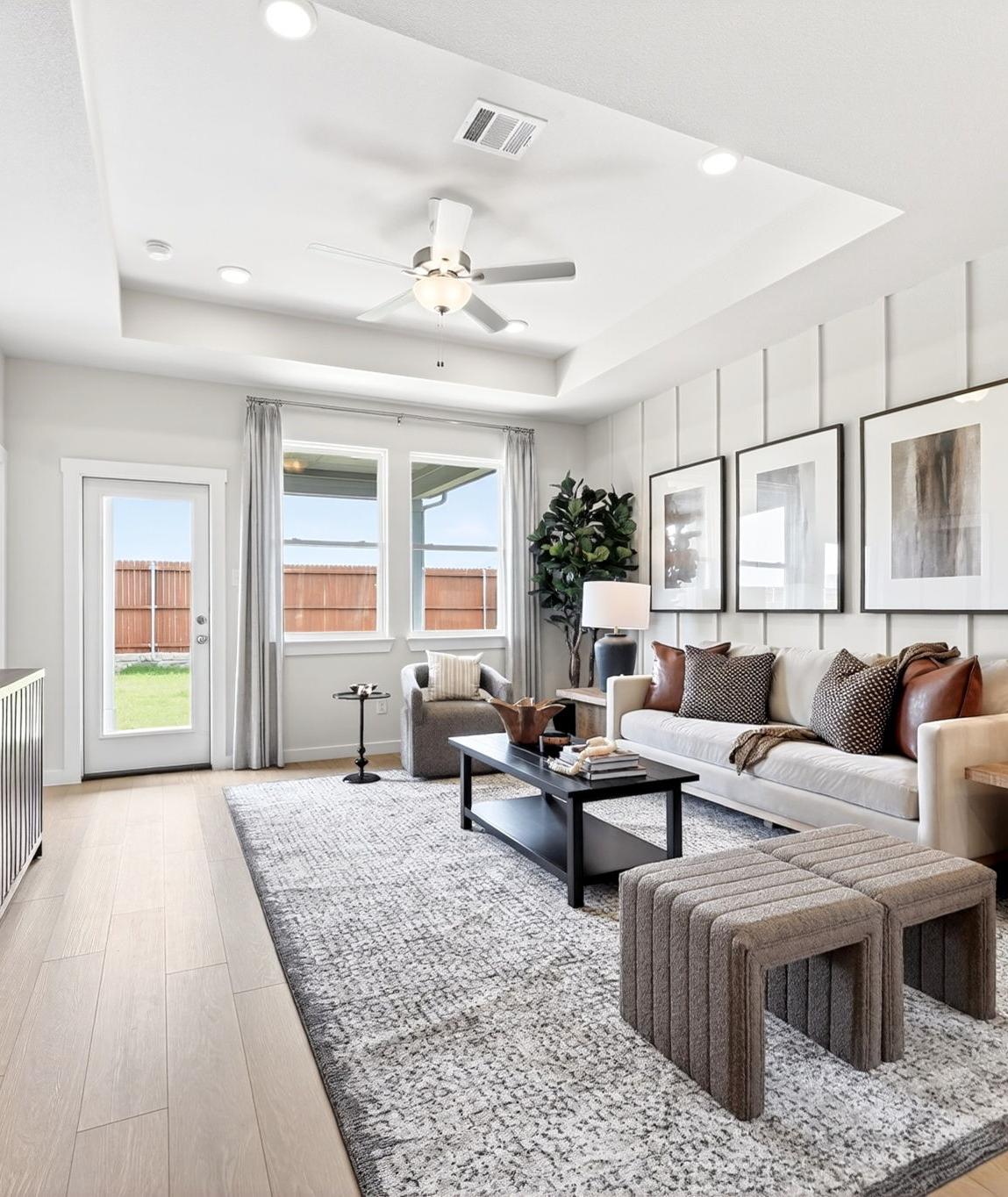 Modern living room in Mesa Vista, San Antonio by Davidson Homes, featuring a tray ceiling, board and batten wall, and decor.