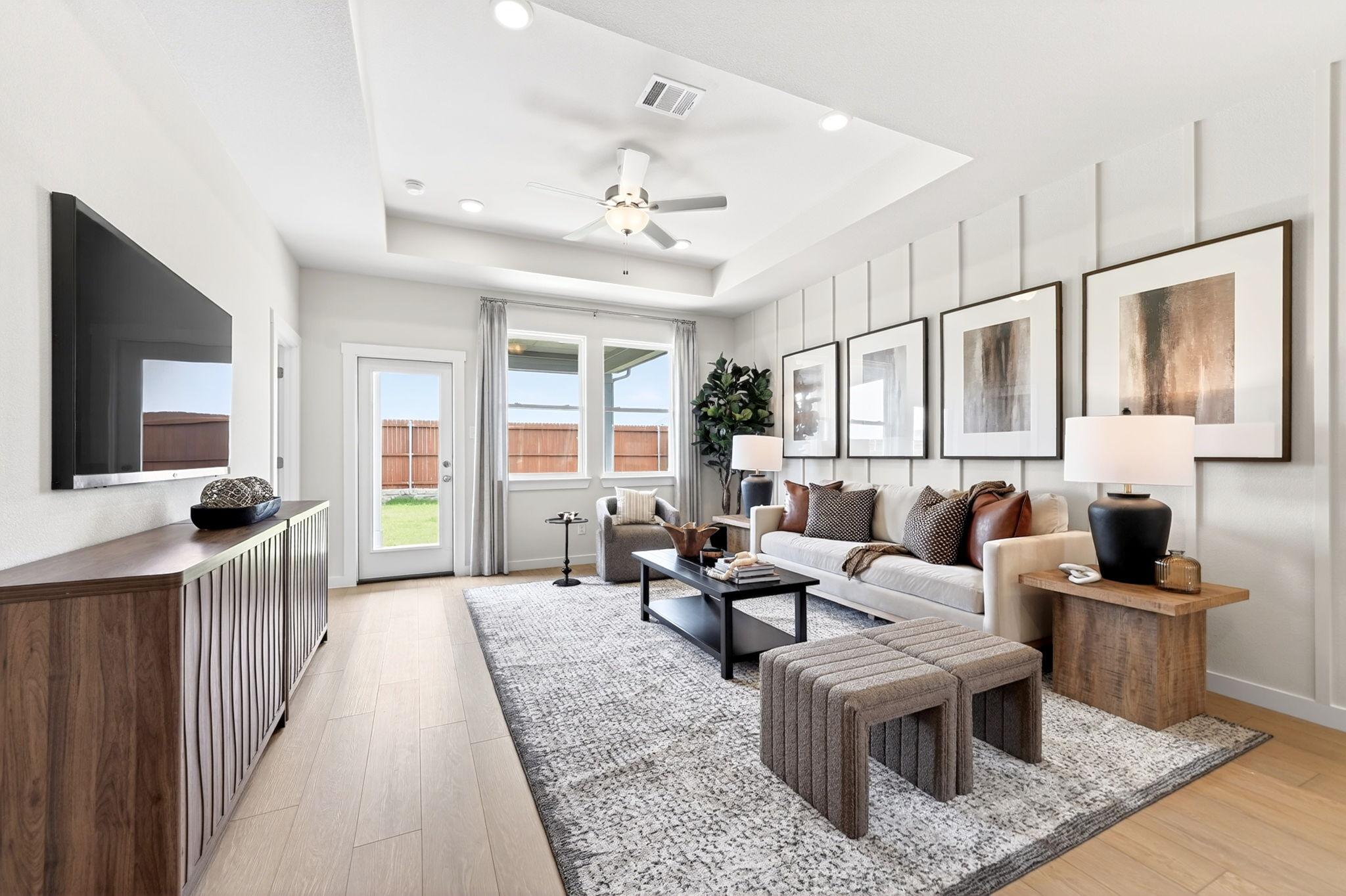 Modern living room in Mesa Vista, San Antonio by Davidson Homes, featuring a tray ceiling, board and batten wall, and decor.