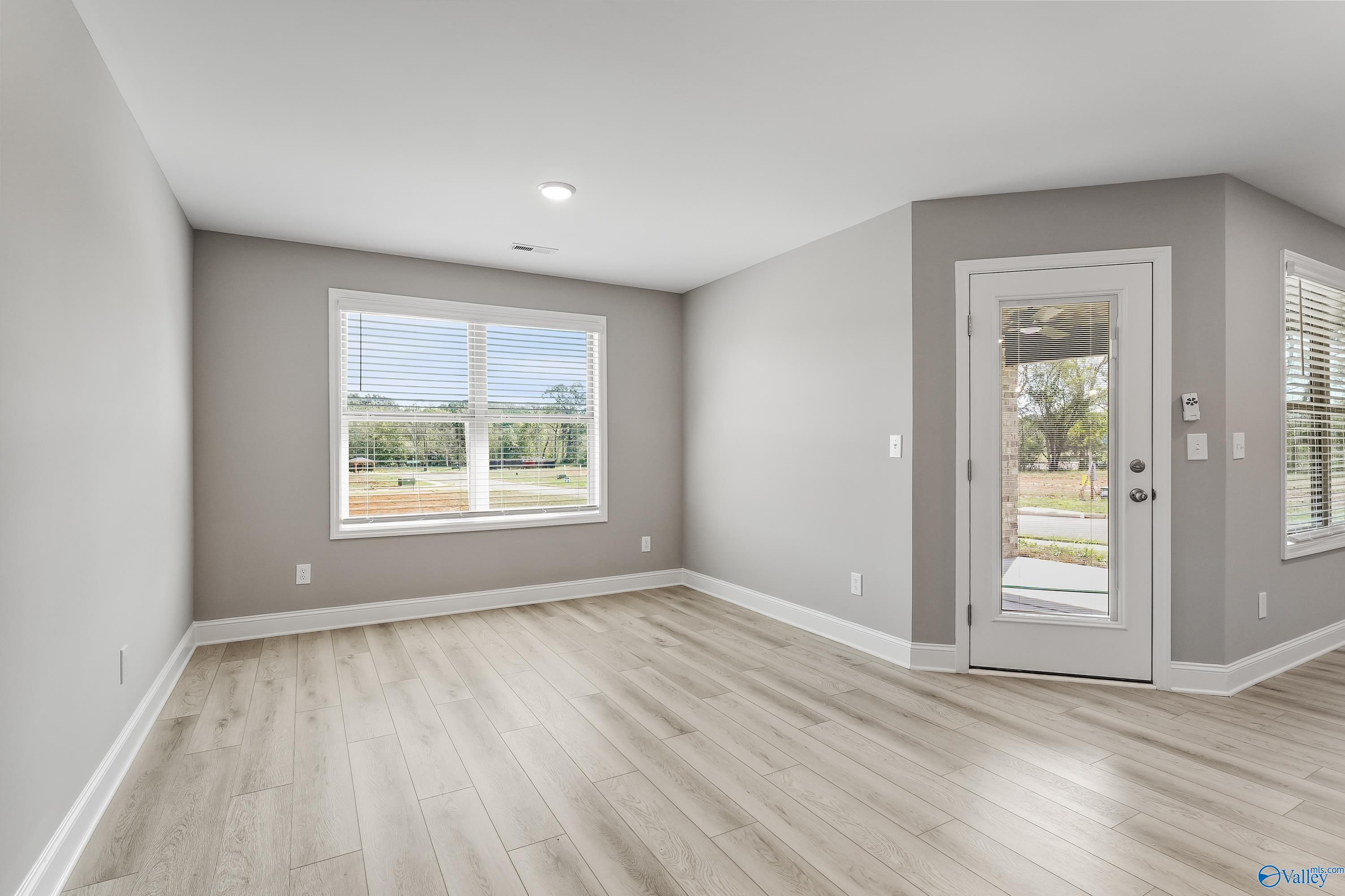 Bright living room with light gray walls, large windows, and glass door to backyard in Davidson Homes The Everett B, Athens Alabama
