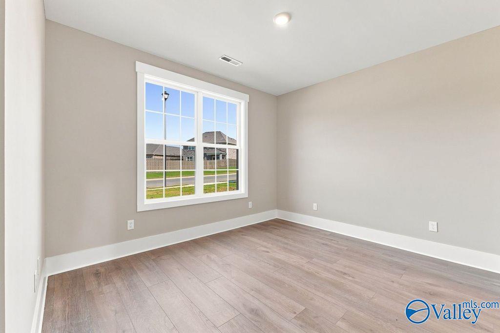 Bright, neutral-toned bedroom with wood-look flooring and large windows in The Rockford floor plan at Cain Park, Hartselle.