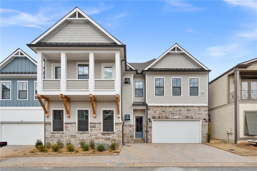 Modern two-story Davidson Homes Seaside B exterior with balcony, stone facade, and 3-car garage in The Village at Towne Lake, Woodstock, Georgia