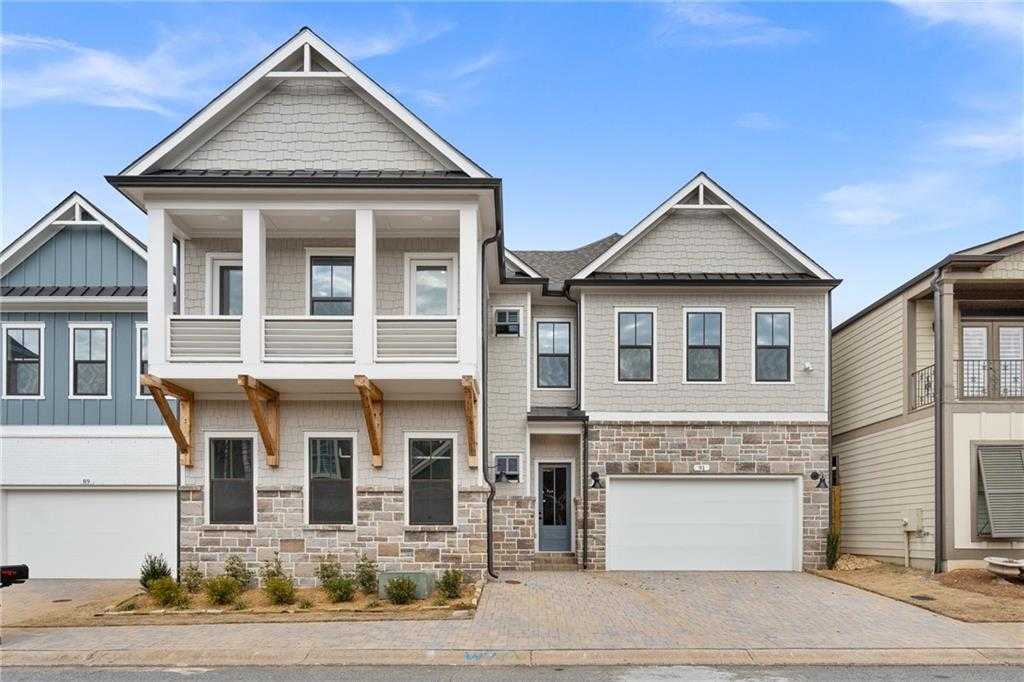Modern two-story Davidson Homes Seaside B exterior with balcony, stone facade, and 3-car garage in The Village at Towne Lake, Woodstock, Georgia