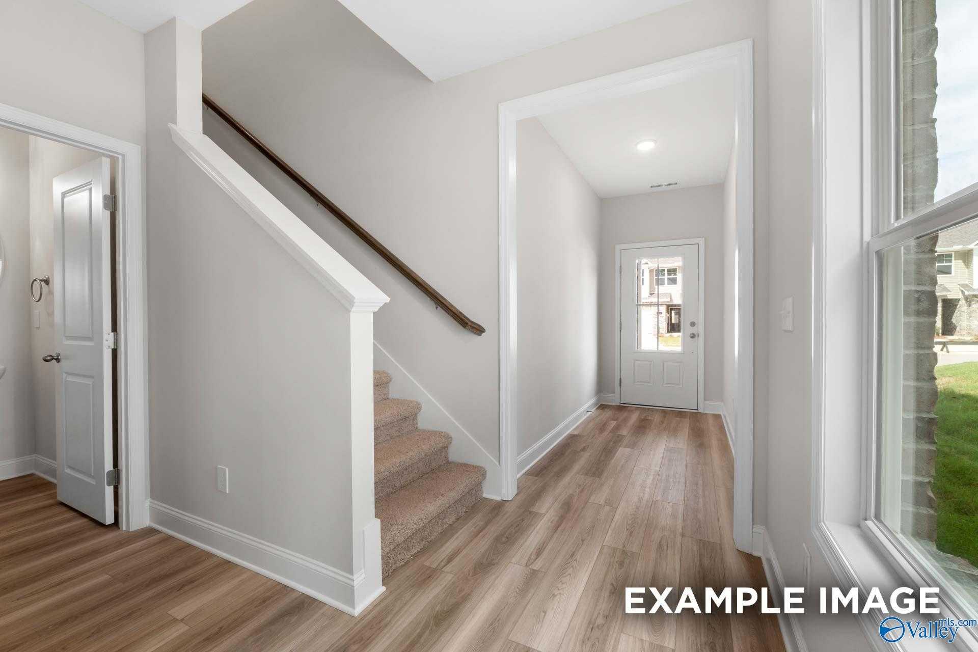 Elegant two-story hallway with oak staircase, hardwood floors and large window in Davidson Homes The Camden, Huntsville, Alabama