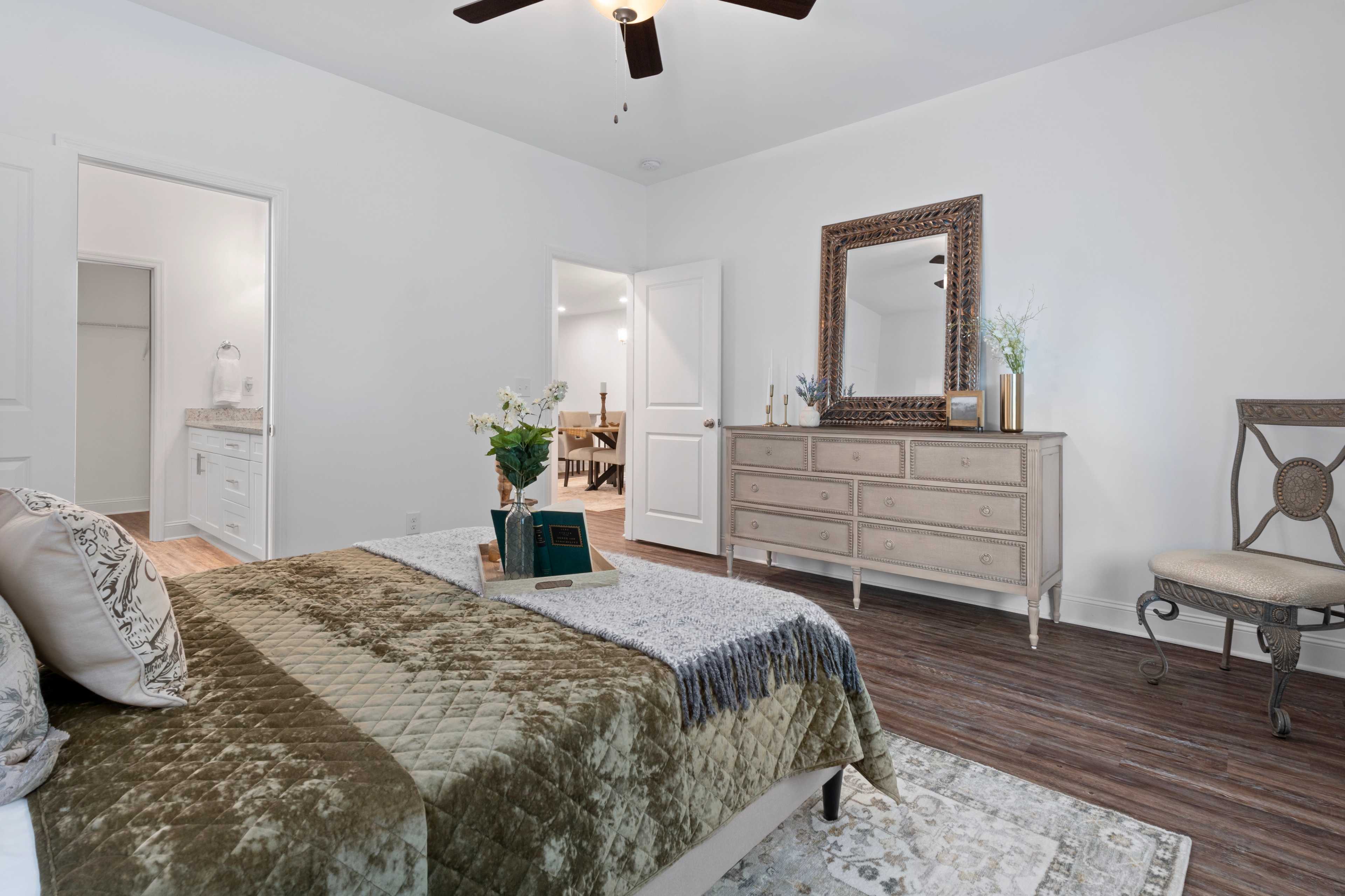 Spacious primary bedroom at The Retreat at Hollon Meadow in Decatur AL with king bed, tufted headboard, dresser, and hardwood floors