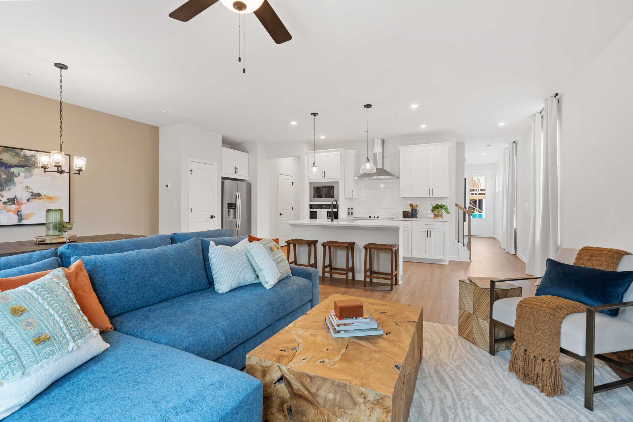 Spacious open-concept living room at Rosehill Townhomes in Marietta GA with blue sectional sofa, wooden coffee table, and white kitchen island
