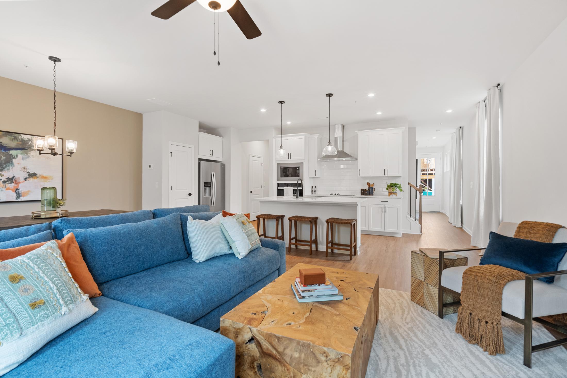 Spacious open-concept living room at Rosehill Townhomes in Marietta GA with blue sectional sofa, wooden coffee table, and white kitchen island