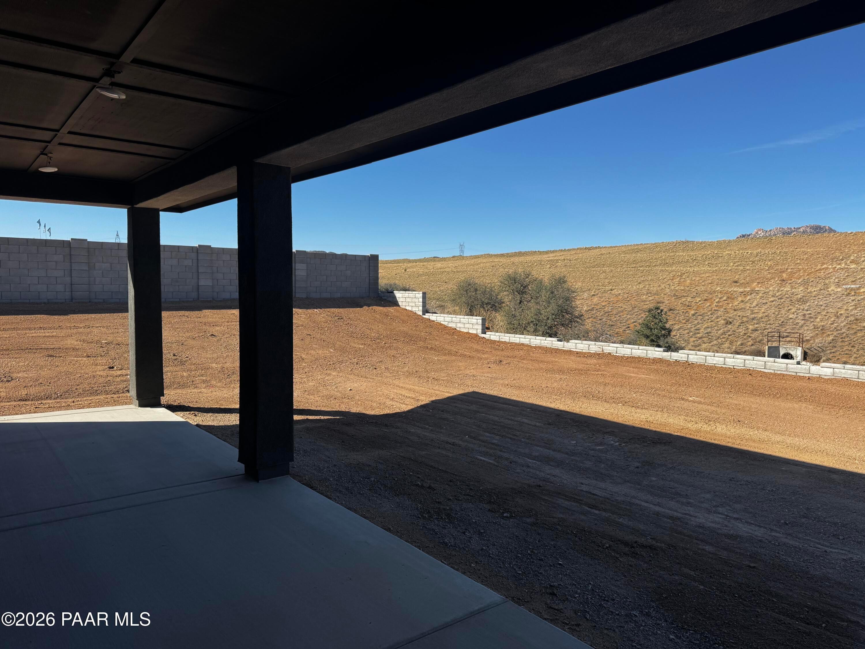 Covered back patio with block walls overlooking desert yard and hills in Hidden Hills, Prescott AZ home