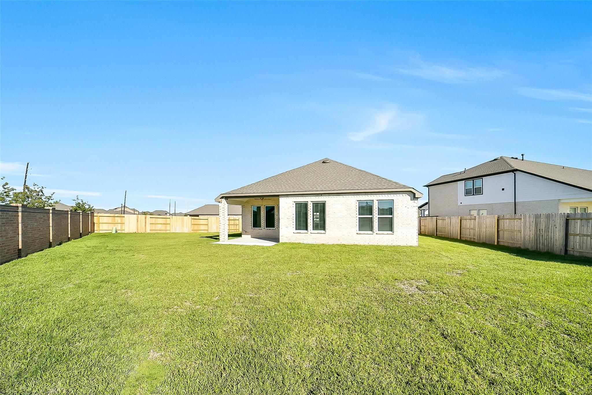 Expansive green backyard with covered patio on single-story 4-bedroom Acadia A home by Davidson Homes in Sunterra, Katy, Texas