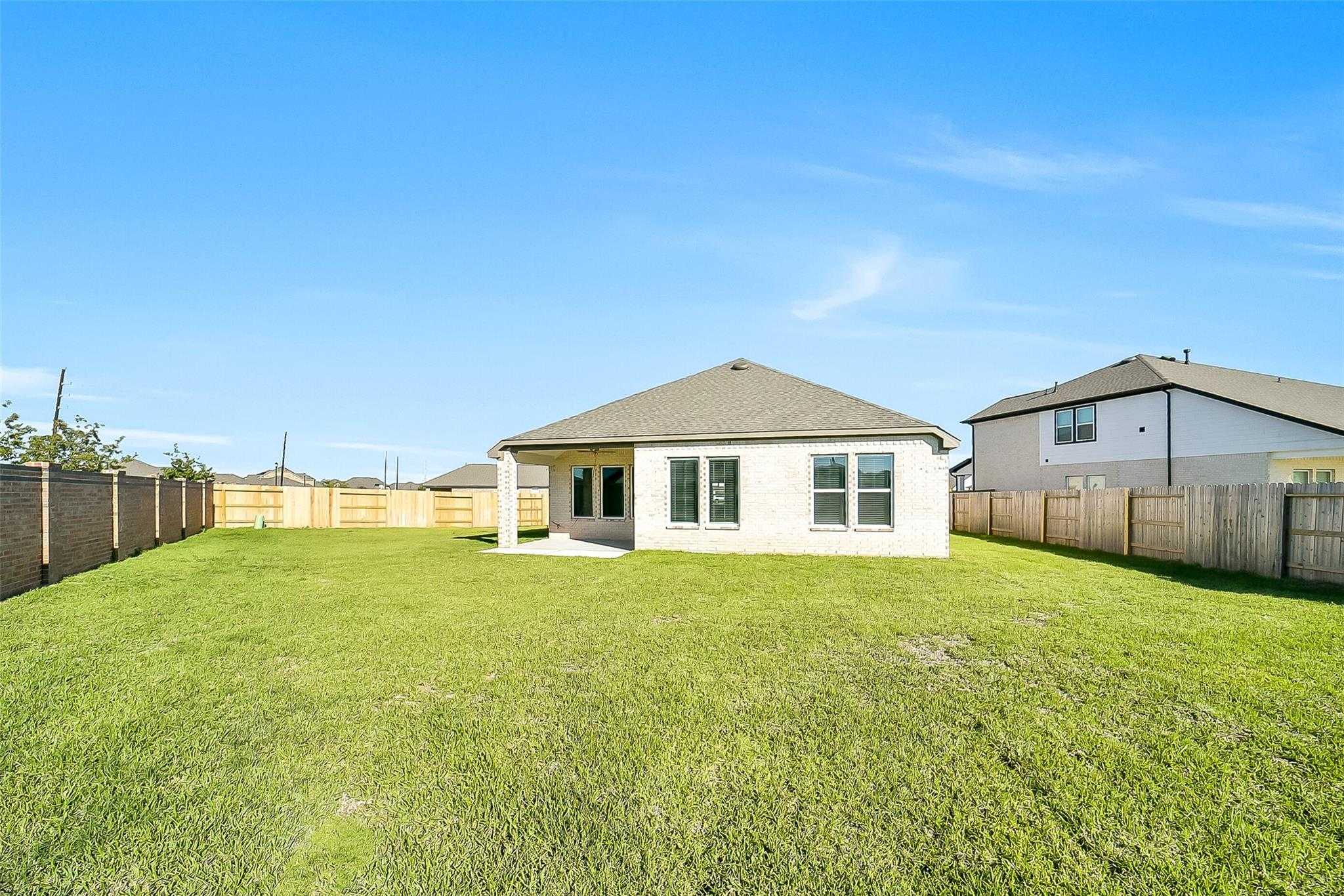 Expansive green backyard with covered patio on single-story 4-bedroom Acadia A home by Davidson Homes in Sunterra, Katy, Texas