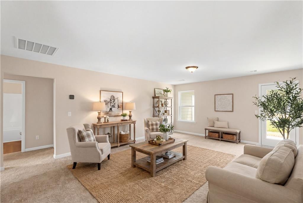 Cozy living room with beige sofa, armchairs, coffee table, and plants in Davidson Homes The Washington, Phenix City, Alabama