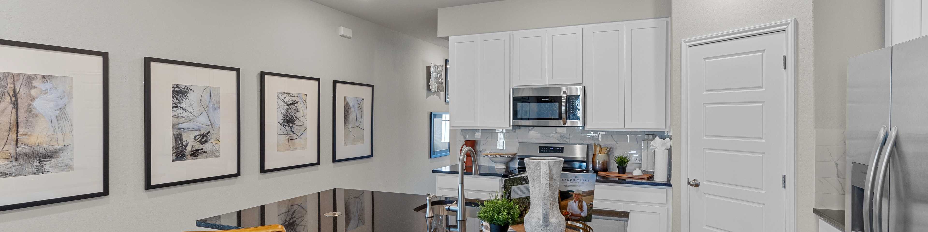 Modern kitchen in Agave San Antonio home by Davidson Homes featuring dark cabinets, granite island, stainless appliances and bar seating