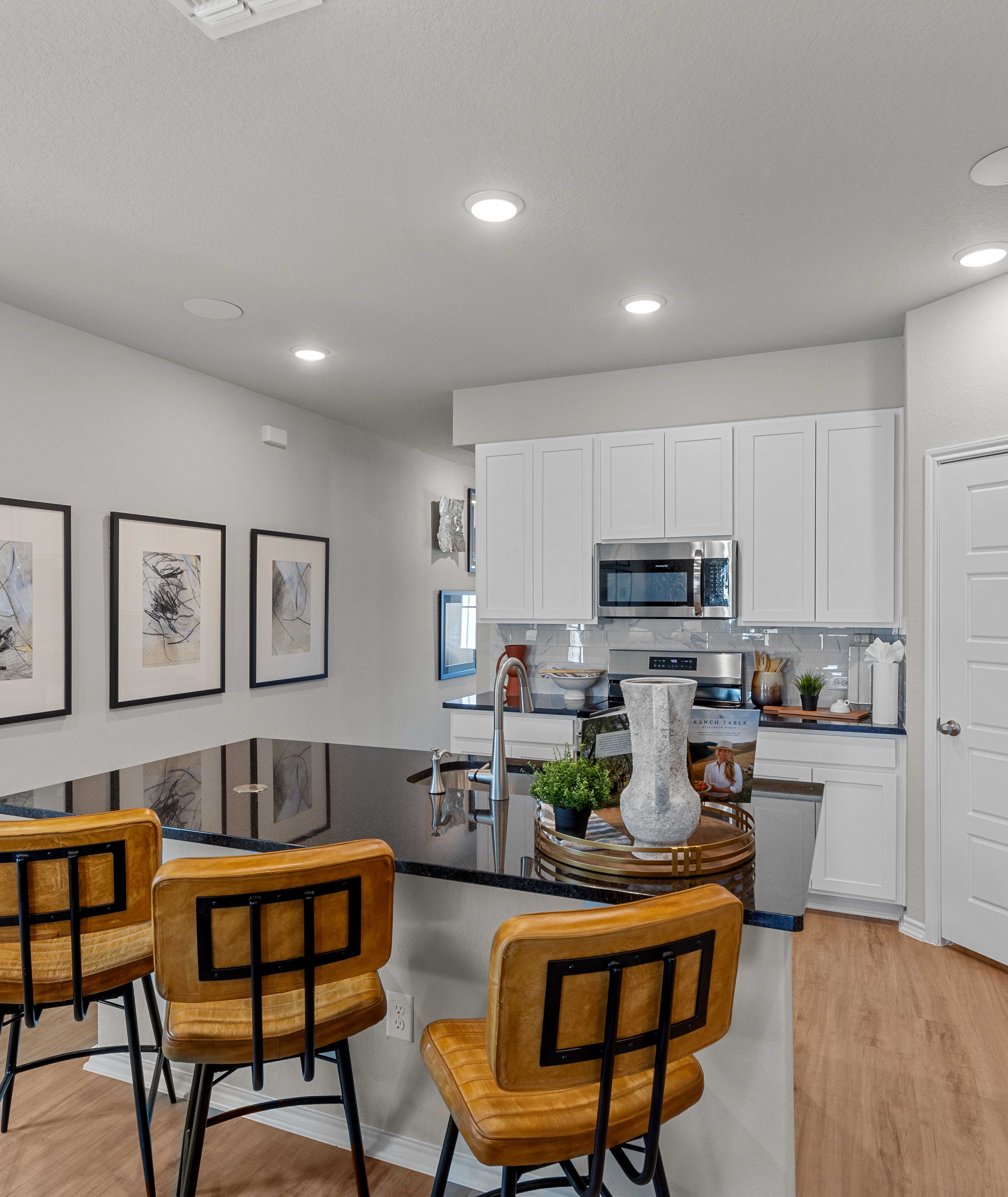 Modern kitchen in Agave San Antonio home by Davidson Homes featuring dark cabinets, granite island, stainless appliances and bar seating