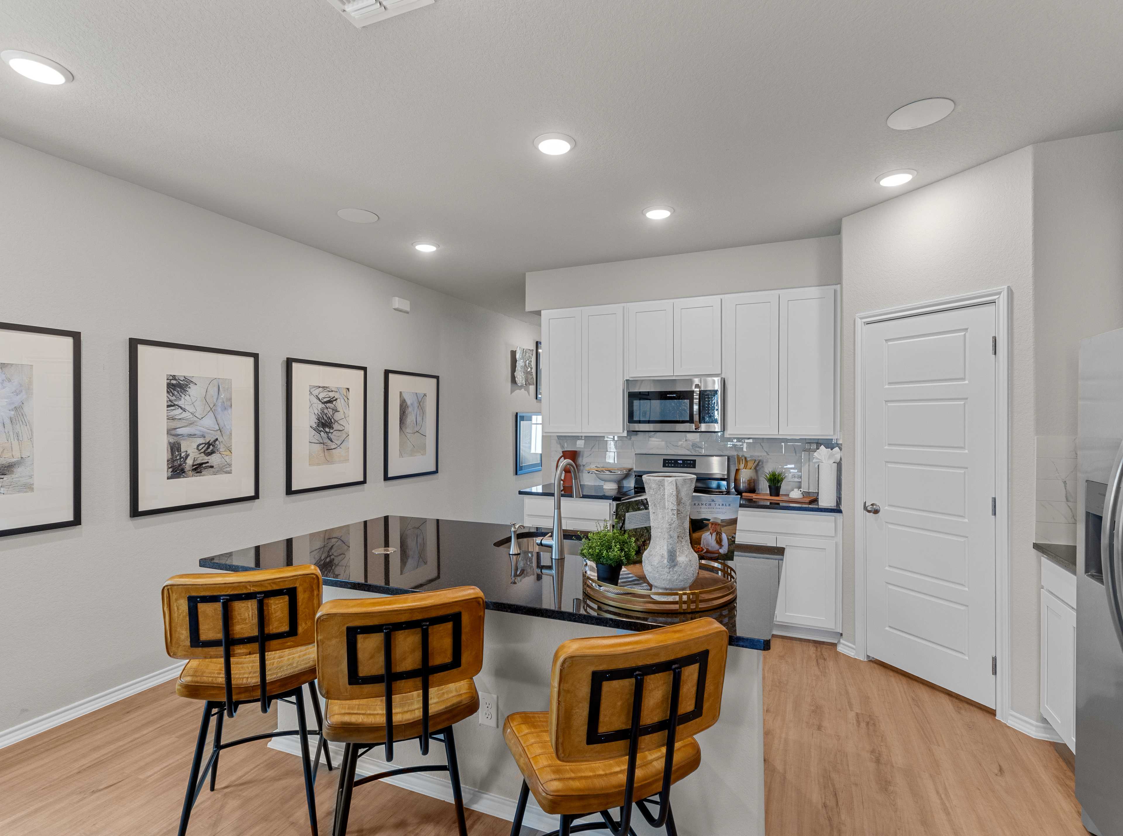 Modern kitchen in Agave San Antonio home by Davidson Homes featuring dark cabinets, granite island, stainless appliances and bar seating