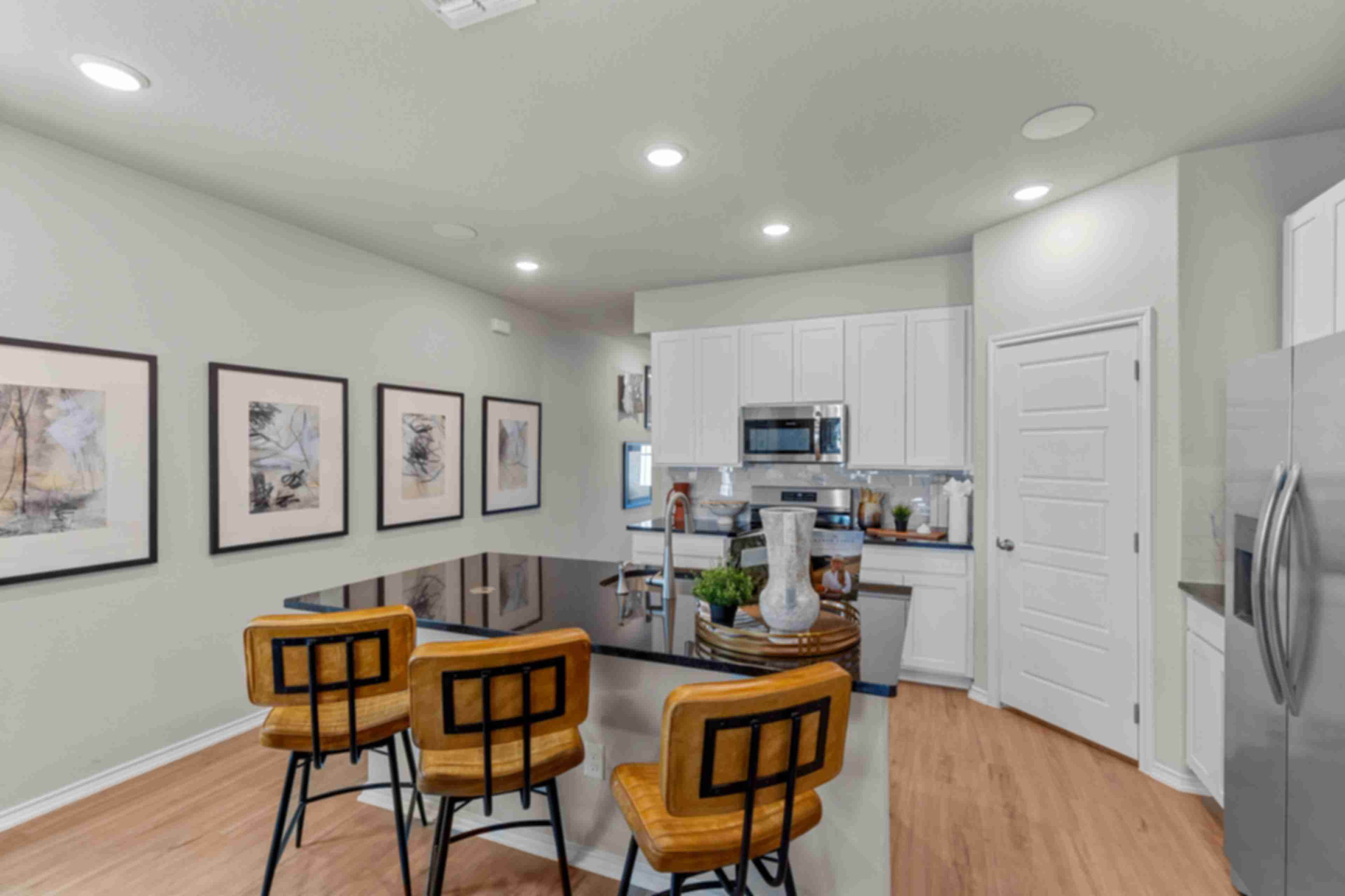 Modern kitchen in Agave San Antonio home by Davidson Homes featuring dark cabinets, granite island, stainless appliances and bar seating