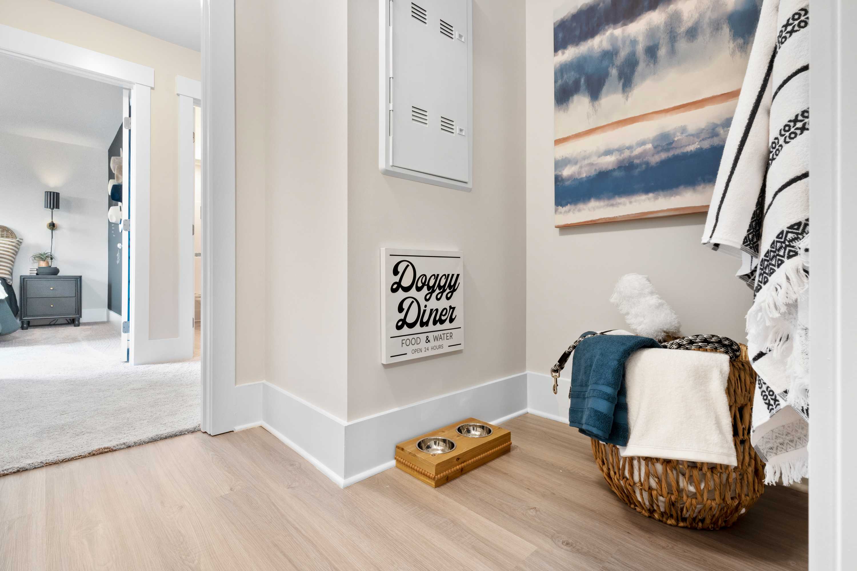 Cozy Doggie Diner pet nook in The Chelsea A home design featuring dog bowls, woven basket towels, and blue abstract wall art