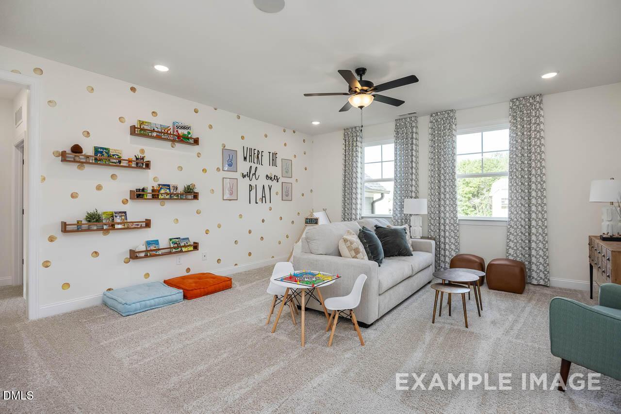 Cozy kids' playroom with polka dot walls, built-in bookshelves, gray sofa, play table in Davidson Homes The Crawford D, Angier, NC