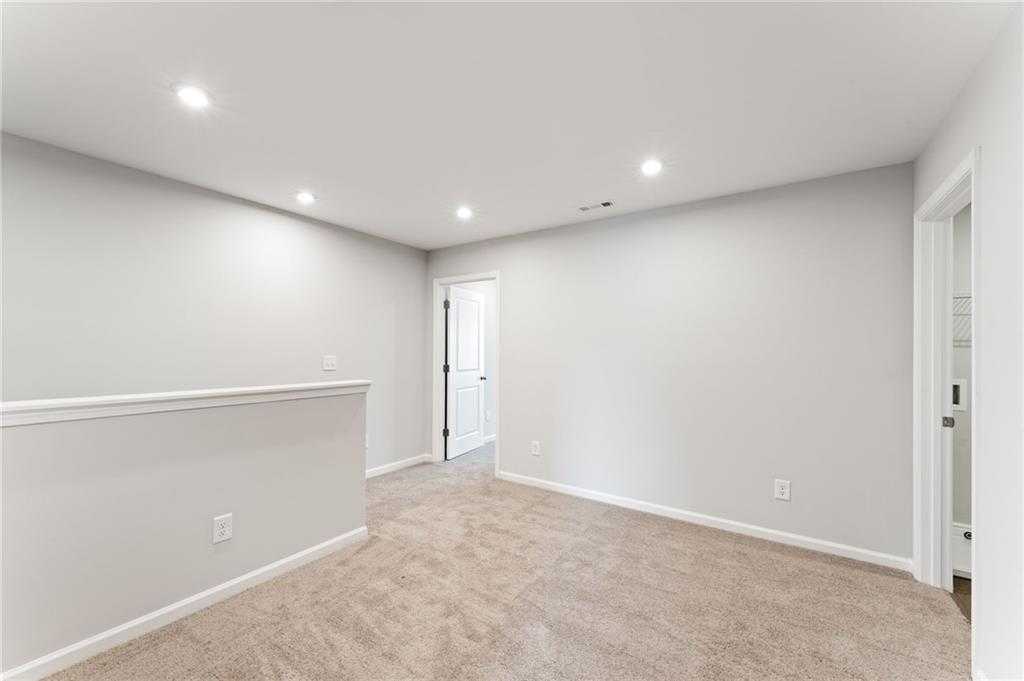 Bright upstairs loft with gray walls, beige carpet, recessed lights, and balcony railing in The Monroe A floor plan, Emerson, GA