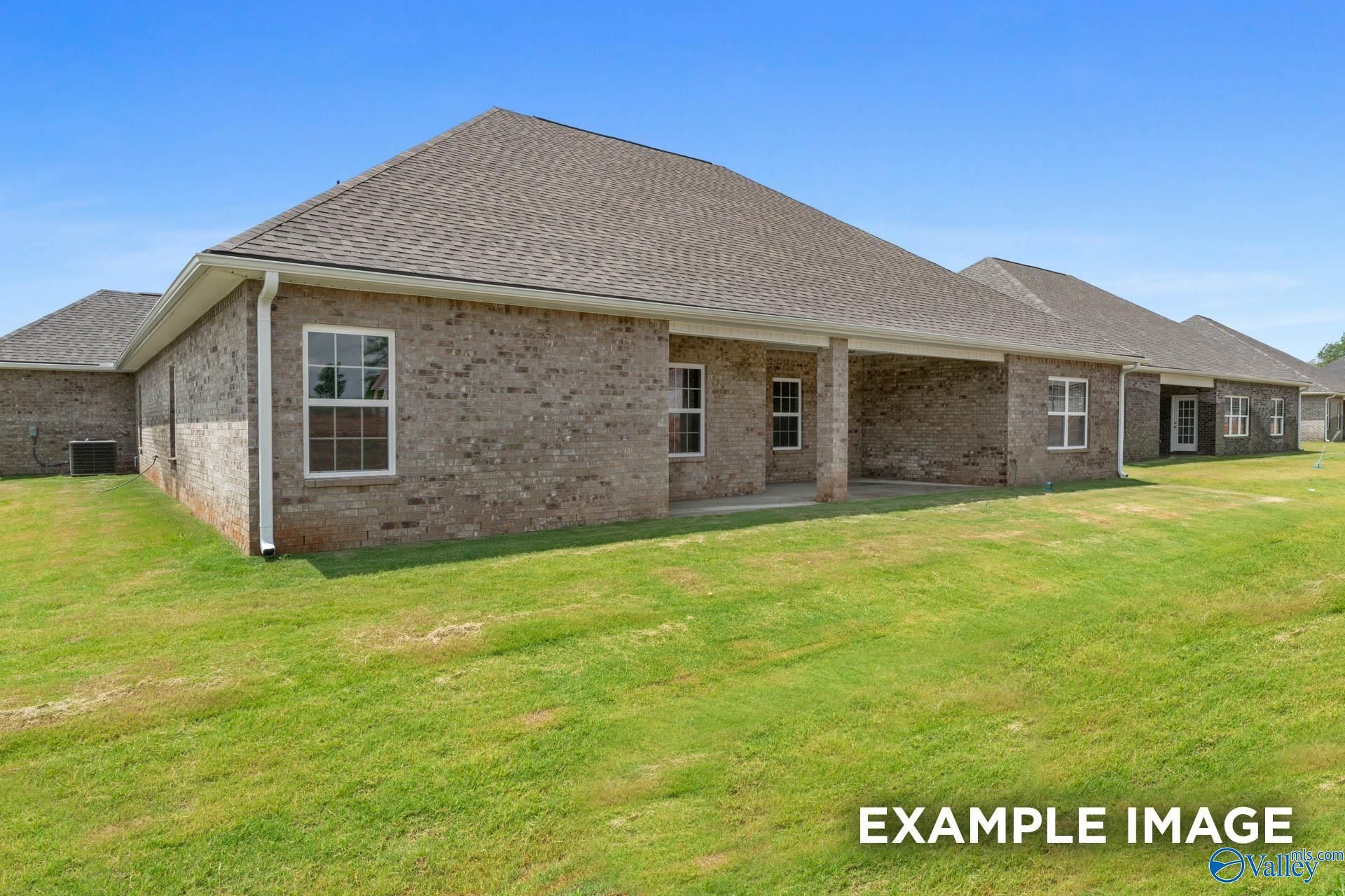 Side view of brick single-story 4-bedroom home with covered patio, shingle roof, and green lawn in Riverton Preserve, Huntsville, Alabama