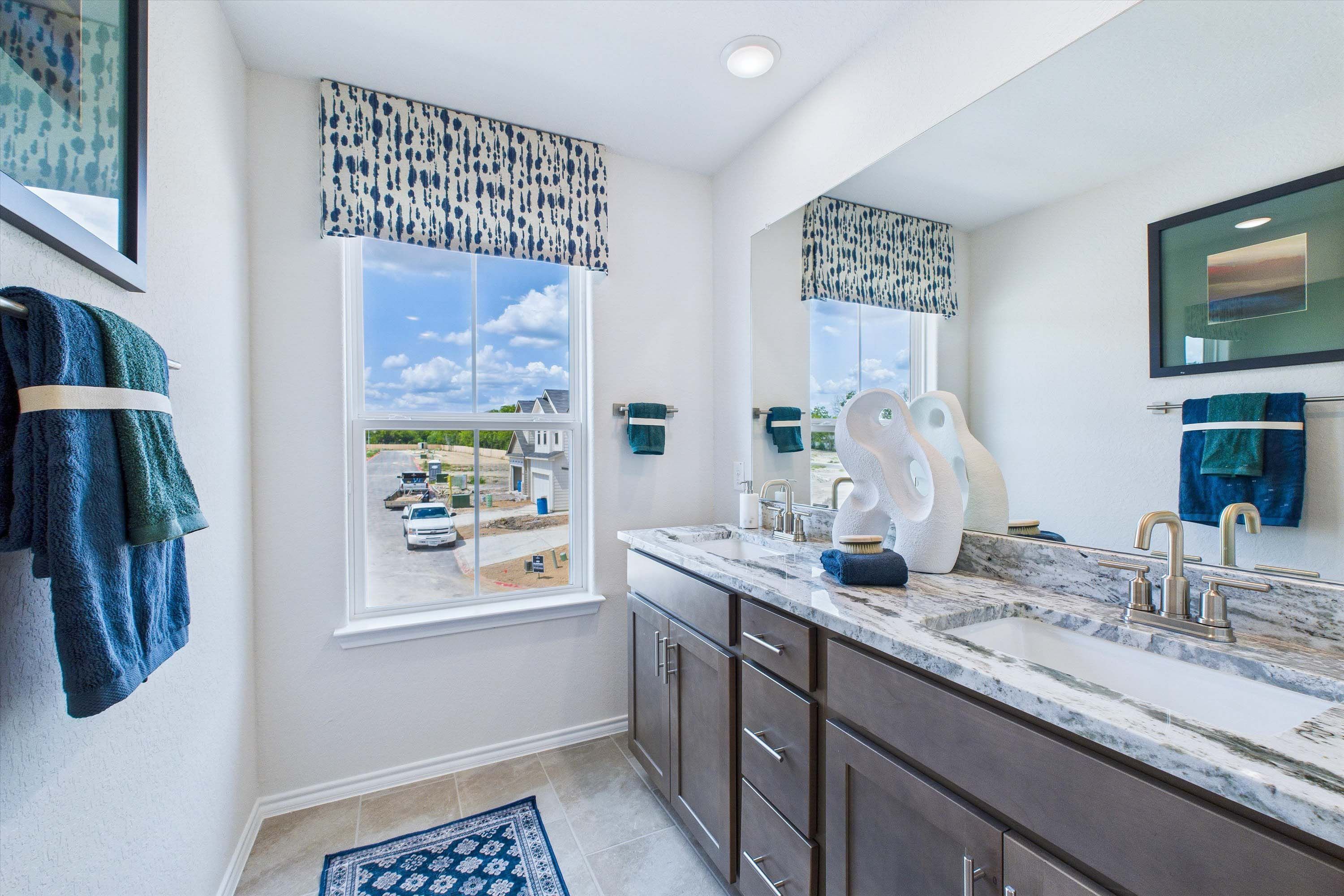 Modern double vanity bathroom in The Gillian C home design featuring granite countertops and contemporary finishes.