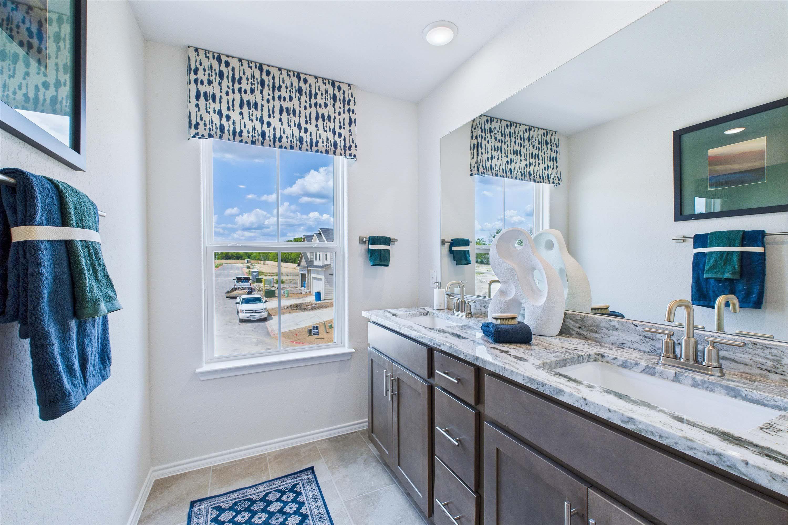 Modern double vanity bathroom in The Gillian C home design featuring granite countertops and contemporary finishes.