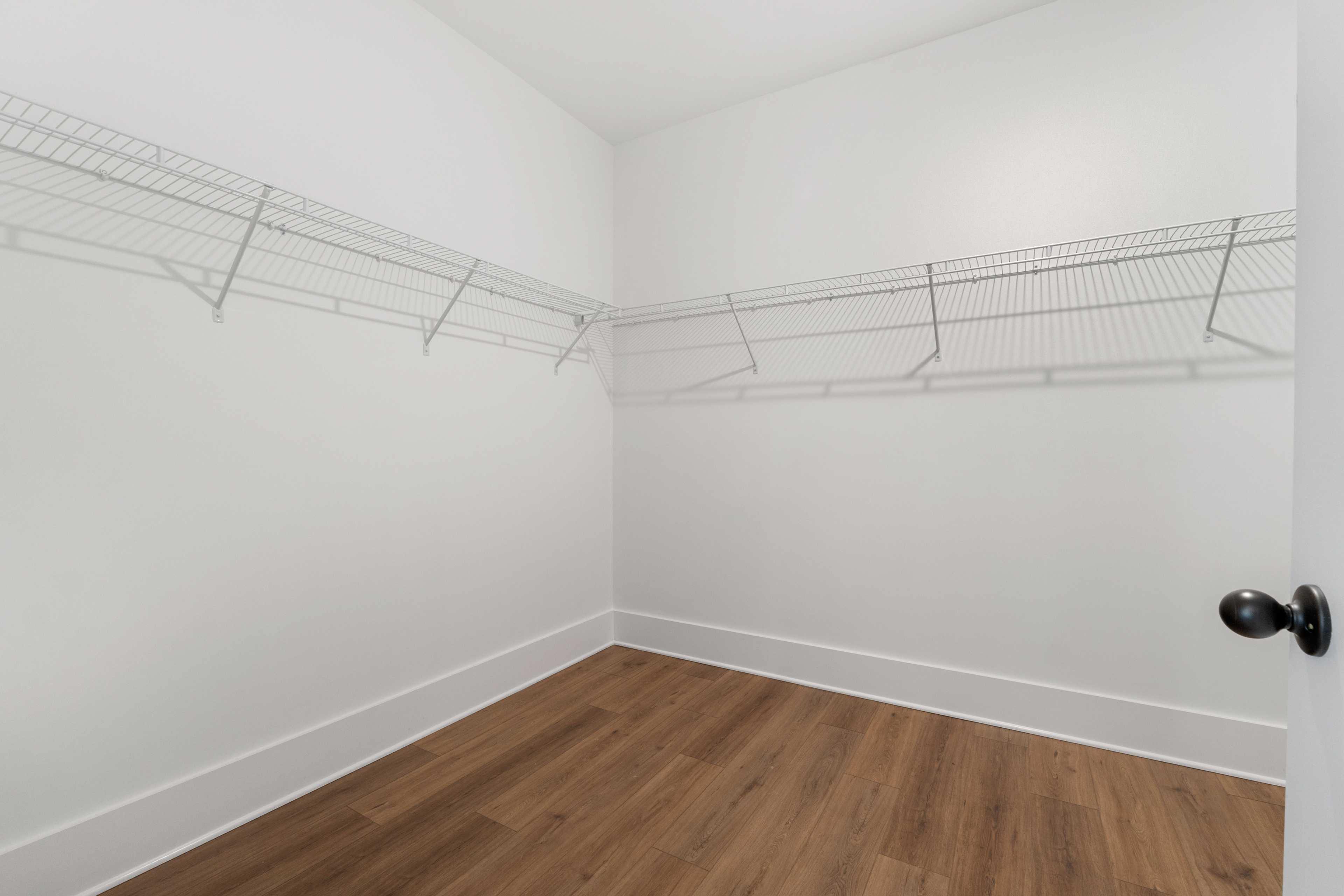 Spacious walk-in closet at Kendall Farms in Toney Alabama with wire shelving and hardwood floors