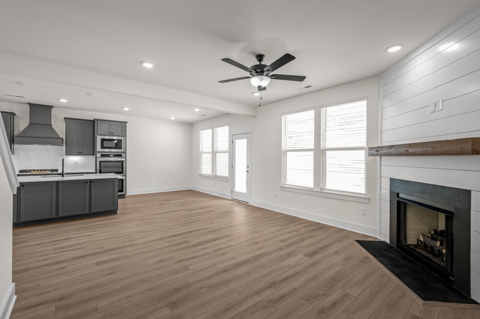 Open-concept living room with shiplap fireplace and modern kitchen in The Willow floor plan at Woods Crossing, Gallatin, TN.