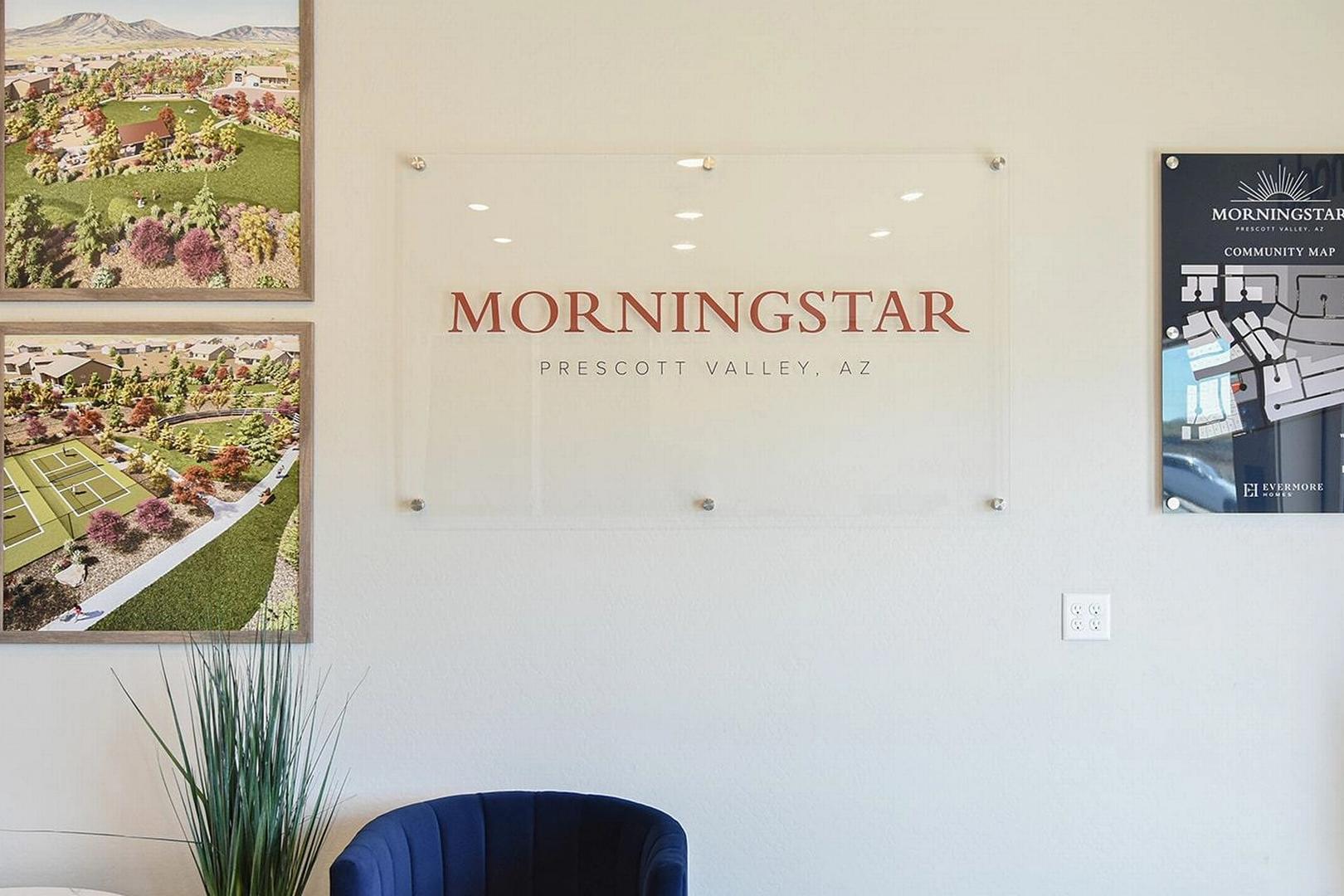Gallery wall with framed aerial views of Morningstar neighborhood in Prescott Valley, AZ, glass sign, plants, and blue chair
