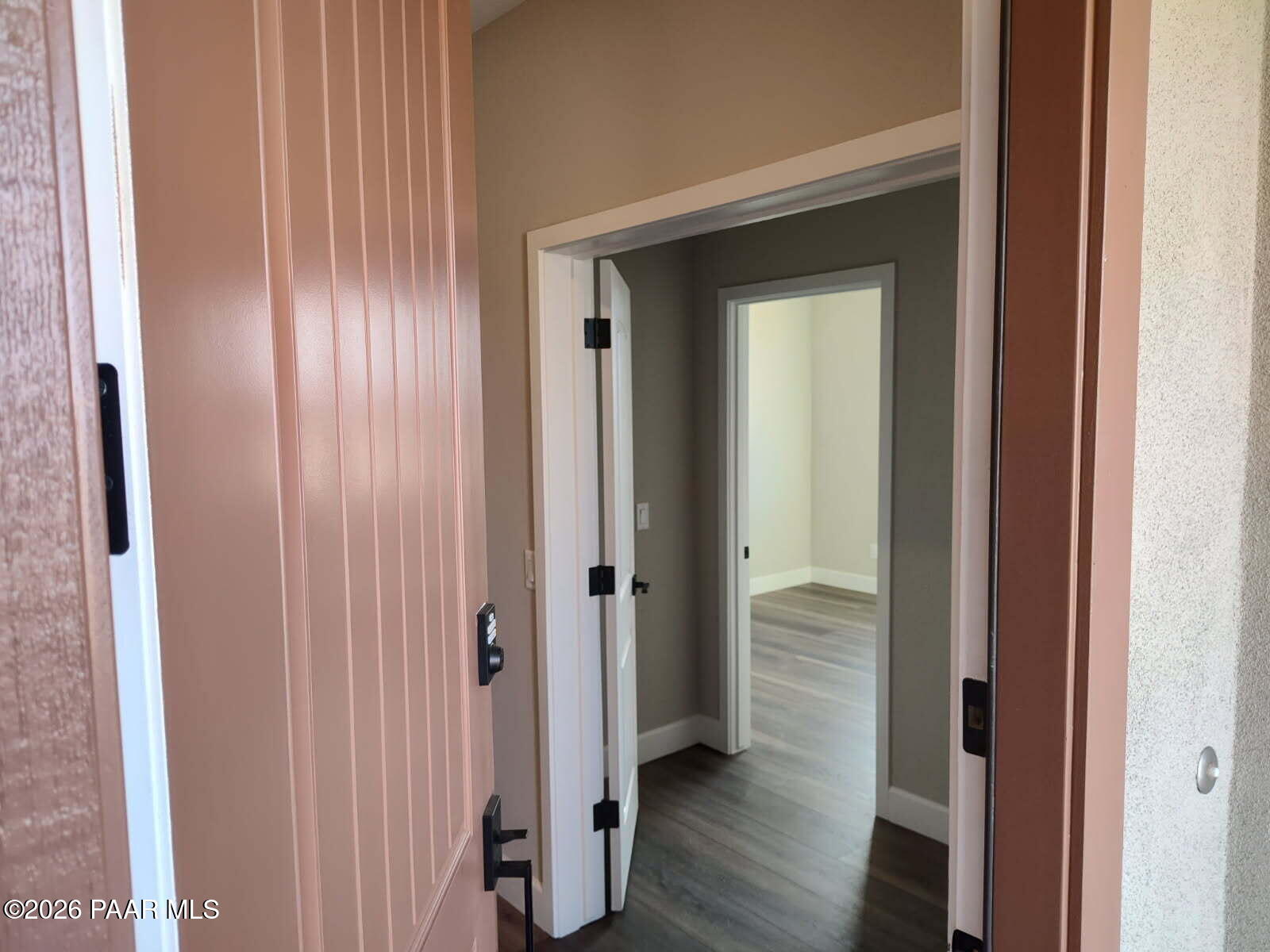 Open entry hallway with paneled tan doors, white bi-fold doors, and luxury vinyl plank flooring in Davidson Homes The Harmony C, Prescott Valley, AZ