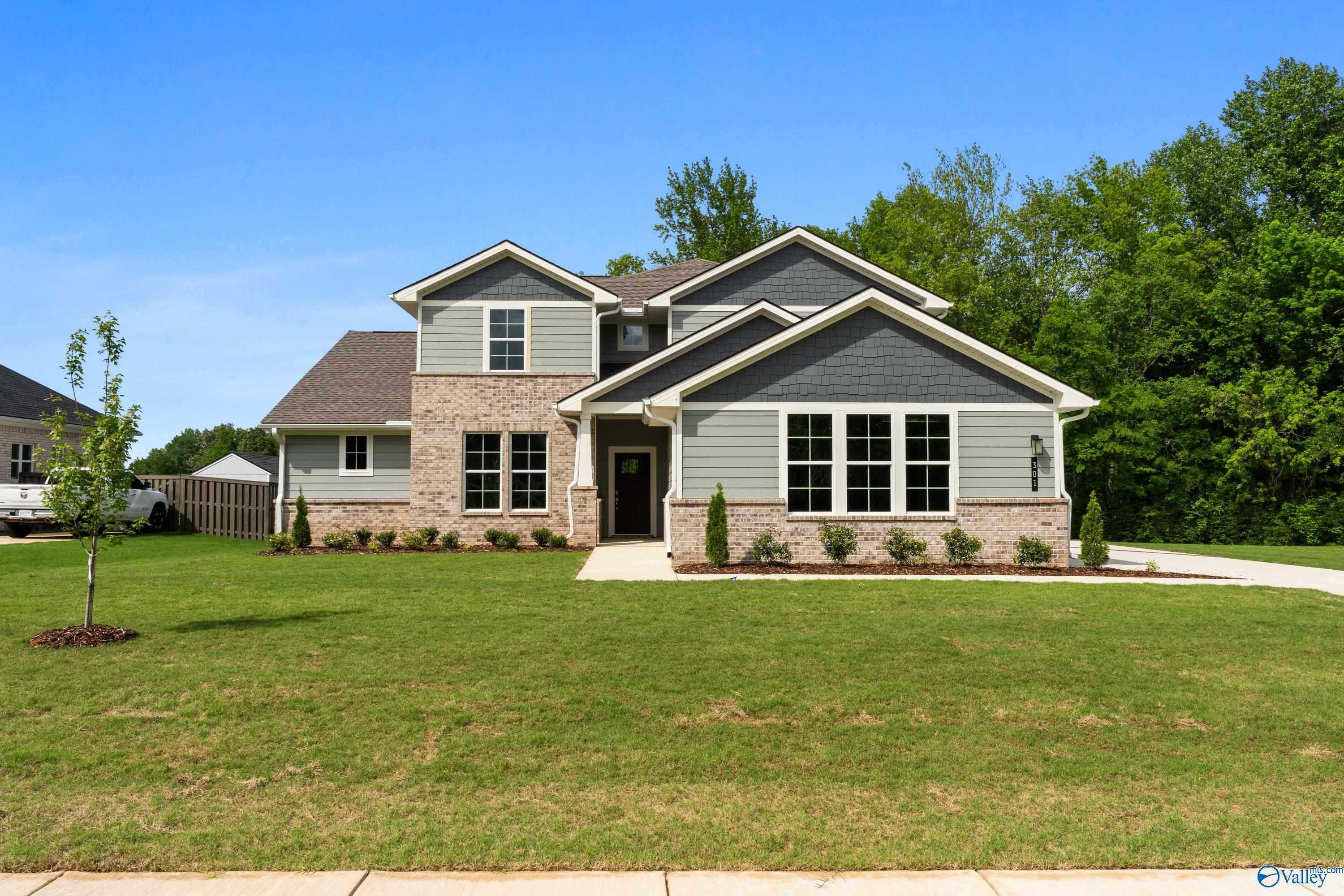 Two-story gray brick home with large windows, landscaped yard and driveway in Riverton Preserve, Huntsville, Alabama