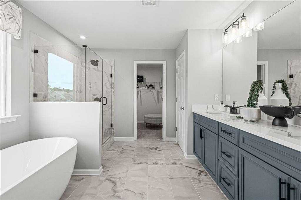 Luxurious master bathroom featuring freestanding tub, glass shower, double vanity with gray cabinets in Davidson Homes The Hickory B, Hoschton, GA