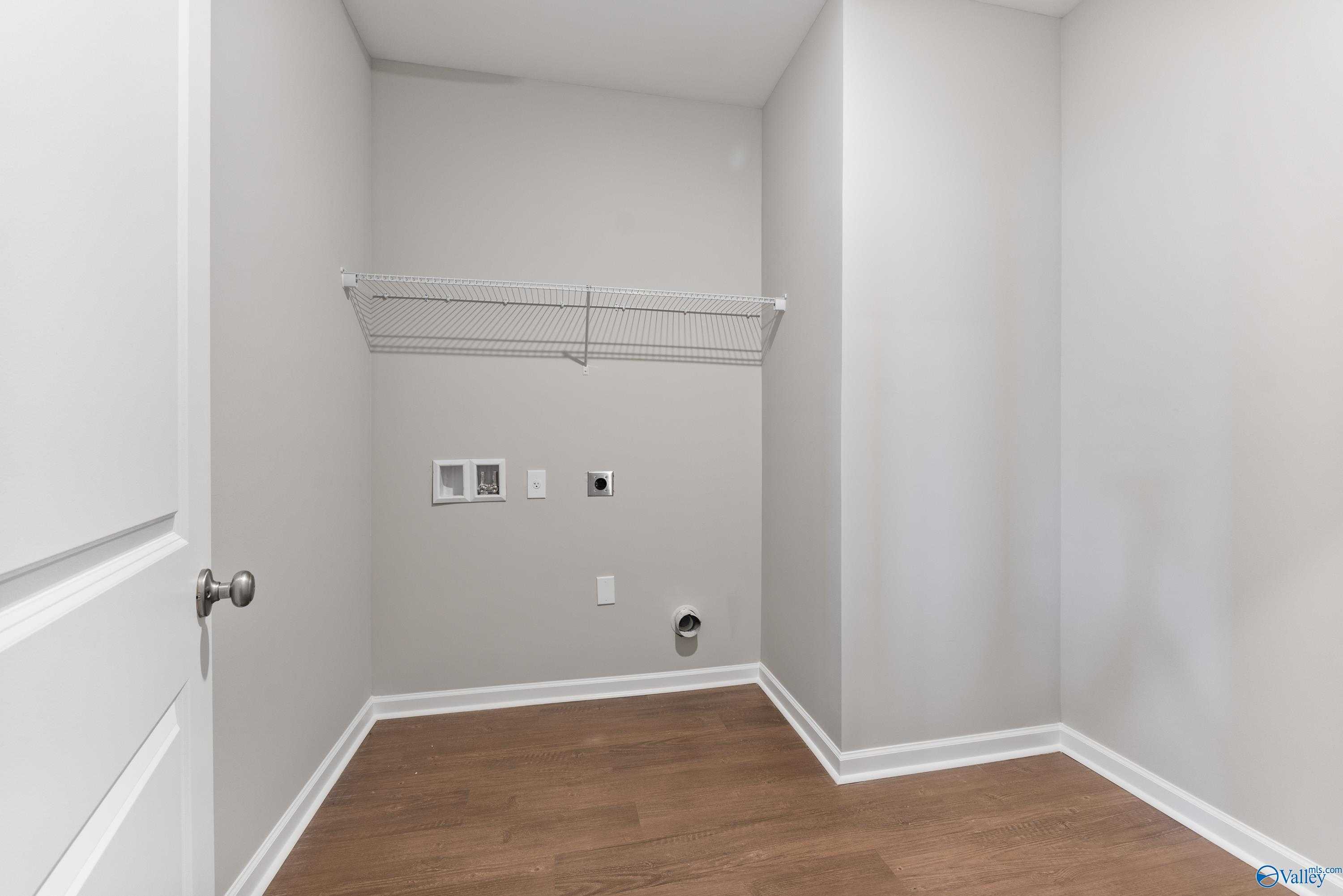 Spacious laundry room with open wire shelving, utility sink, washer dryer hookups and hardwood floors in Davidson Homes The Sanctuary, Huntsville AL