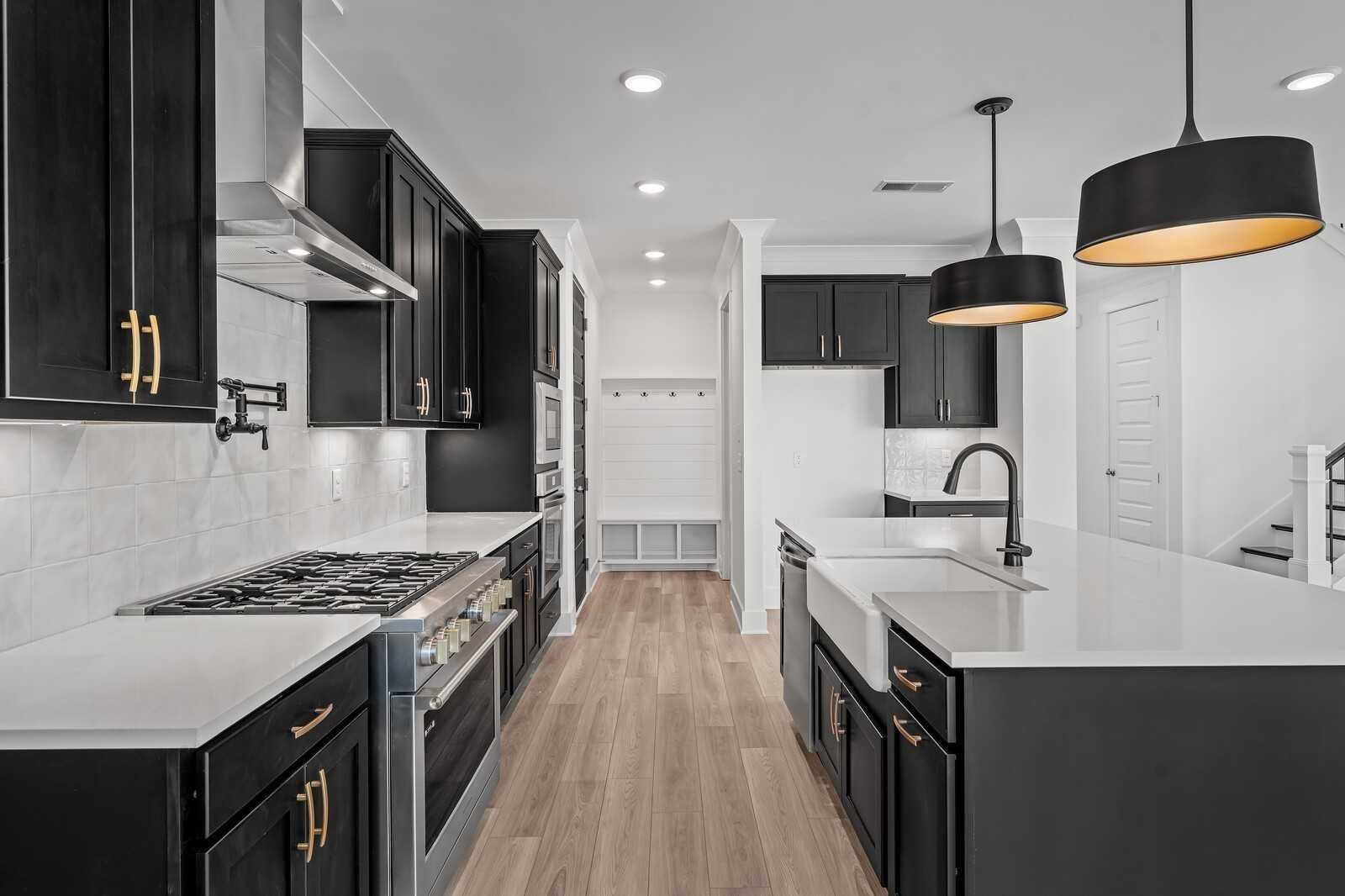 Modern kitchen with black cabinets, white quartz counters, farmhouse sink, and stainless appliances in Davidson Homes The Hathaway, Murfreesboro