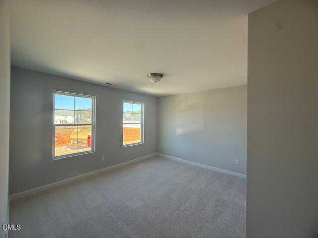 Spacious empty bedroom with gray walls, beige carpet, and large windows in Davidson Homes The Gavin B, Lillington, NC