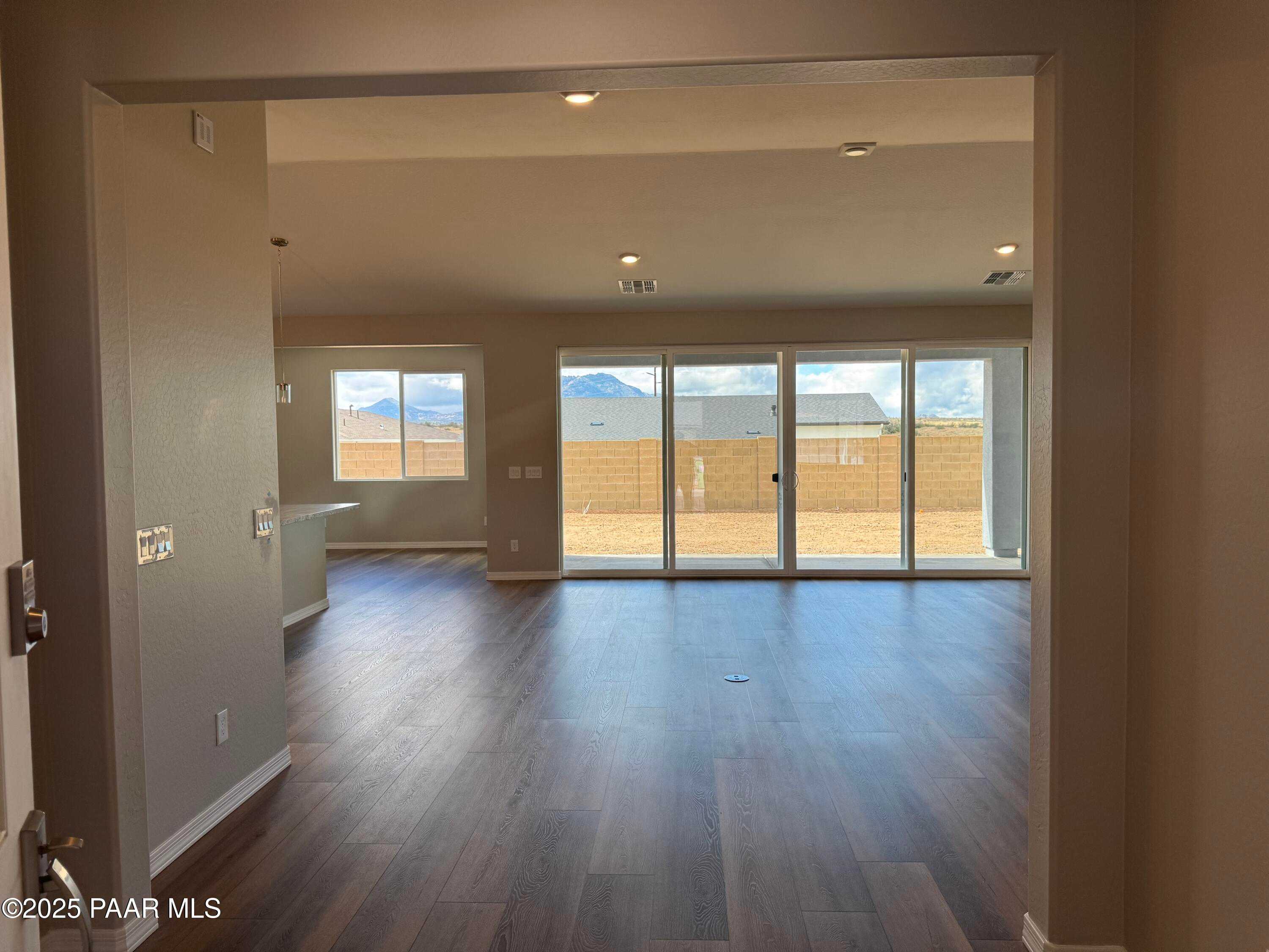 Open-concept living room with hardwood floors, large sliding doors to desert mountain view in 3-bed Prescott AZ home
