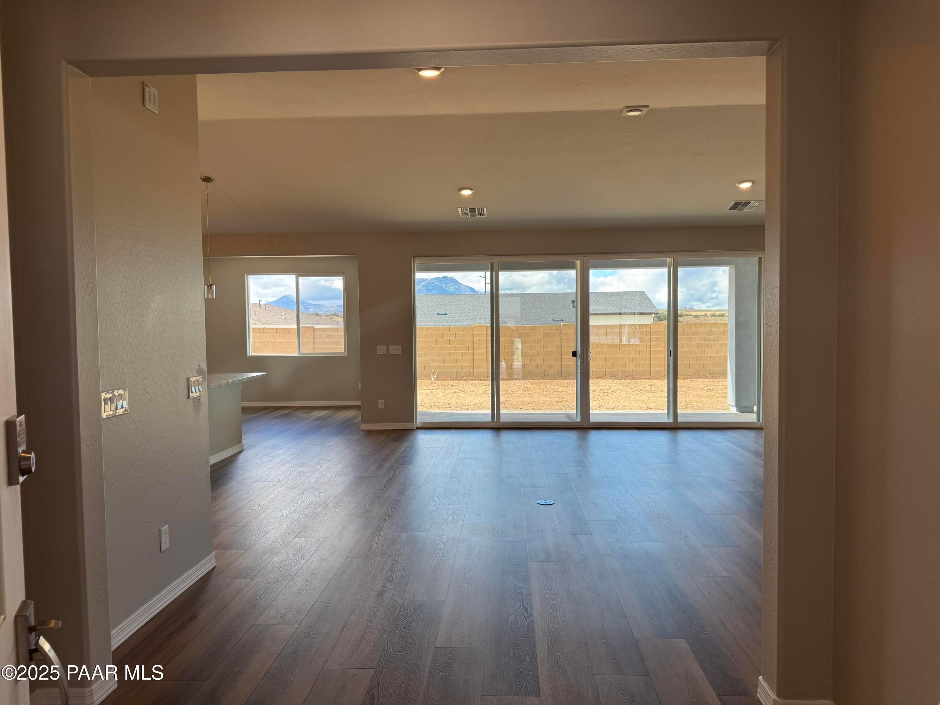 Open-concept living room with hardwood floors, large sliding doors to desert mountain view in 3-bed Prescott AZ home