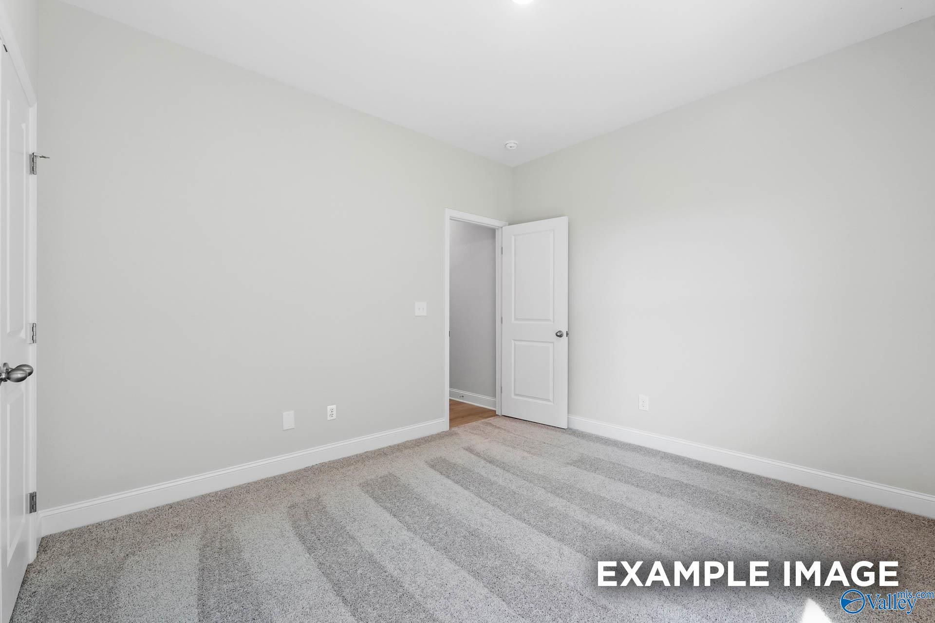 Neutral-toned spare bedroom with plush carpeting in The Everett B floor plan by Davidson Homes in Athens, Alabama.