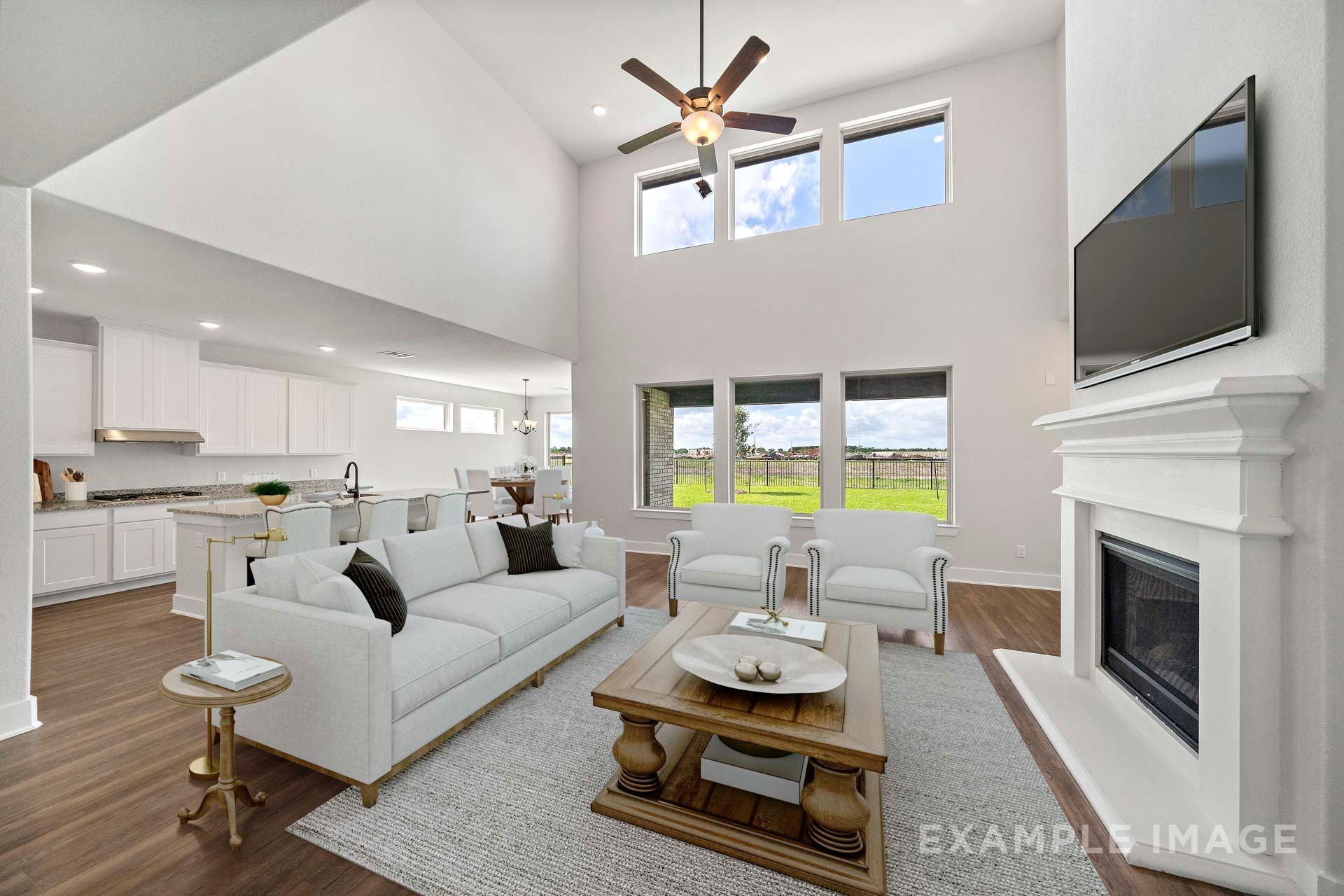 Two-story great room in The Victoria with fireplace, white kitchen, and open-concept living area by Davidson Homes Texas City.