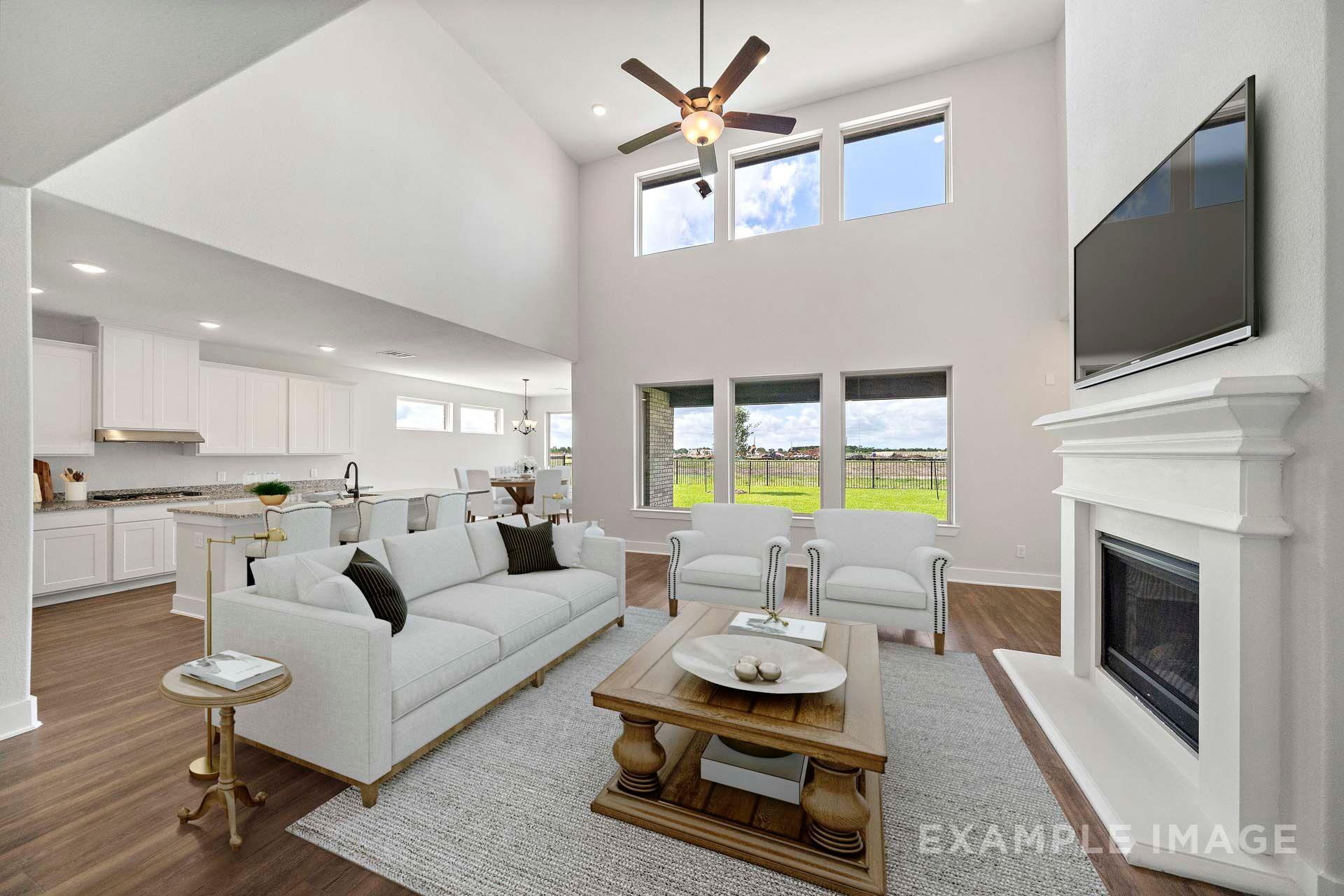 Two-story great room in The Victoria with fireplace, white kitchen, and open-concept living area by Davidson Homes Texas City.