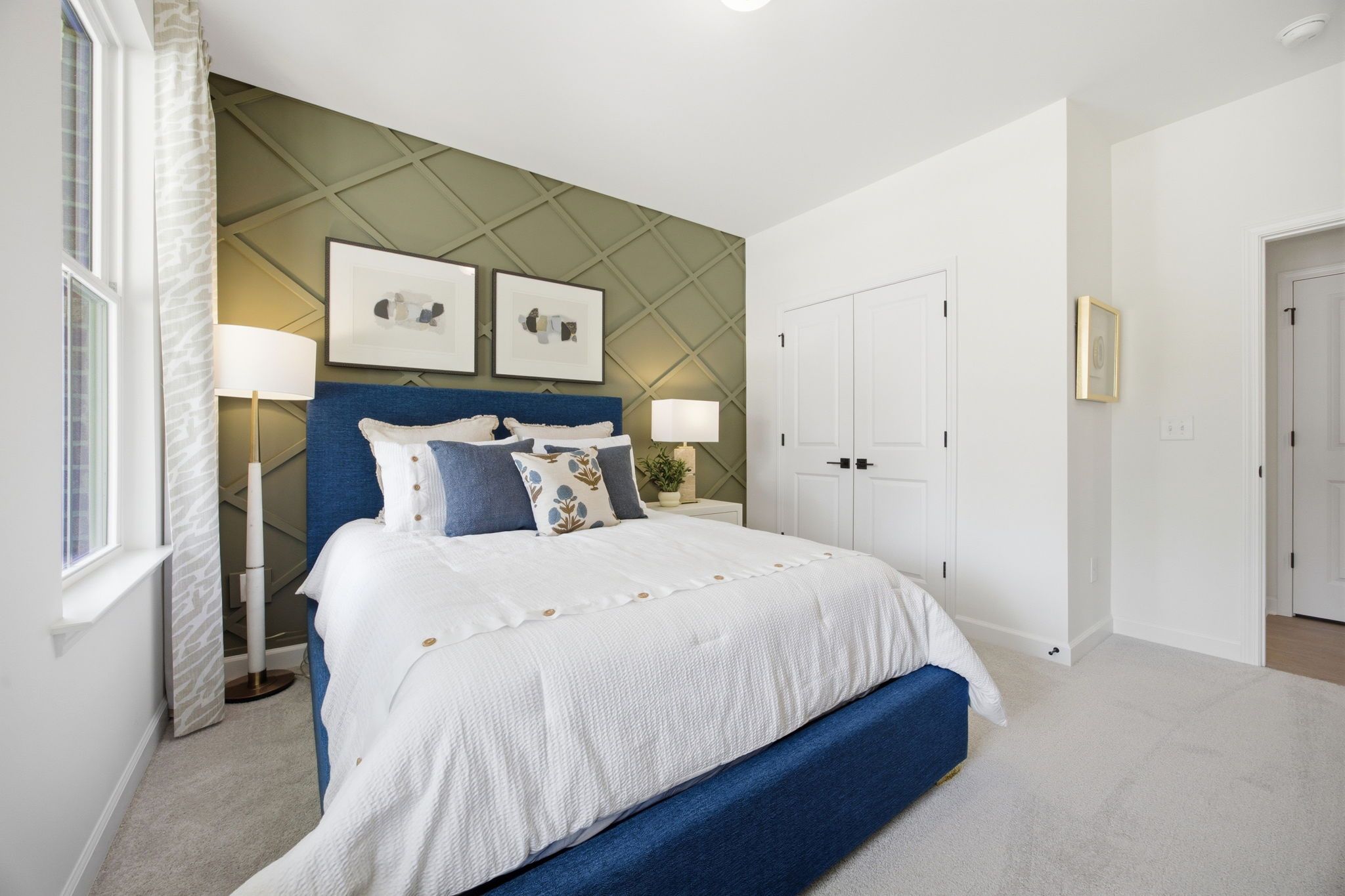 Master bedroom in The Ashport with blue upholstered bed, accent wall, and cozy decor in a new Wendell, NC home.