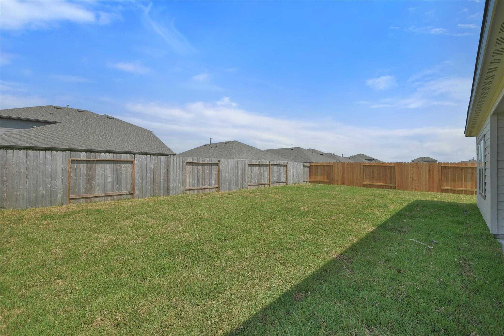 Private backyard with lush green lawn and wooden privacy fence in Davidson Homes The Tierra A, River Ranch Meadows, Dayton, Texas