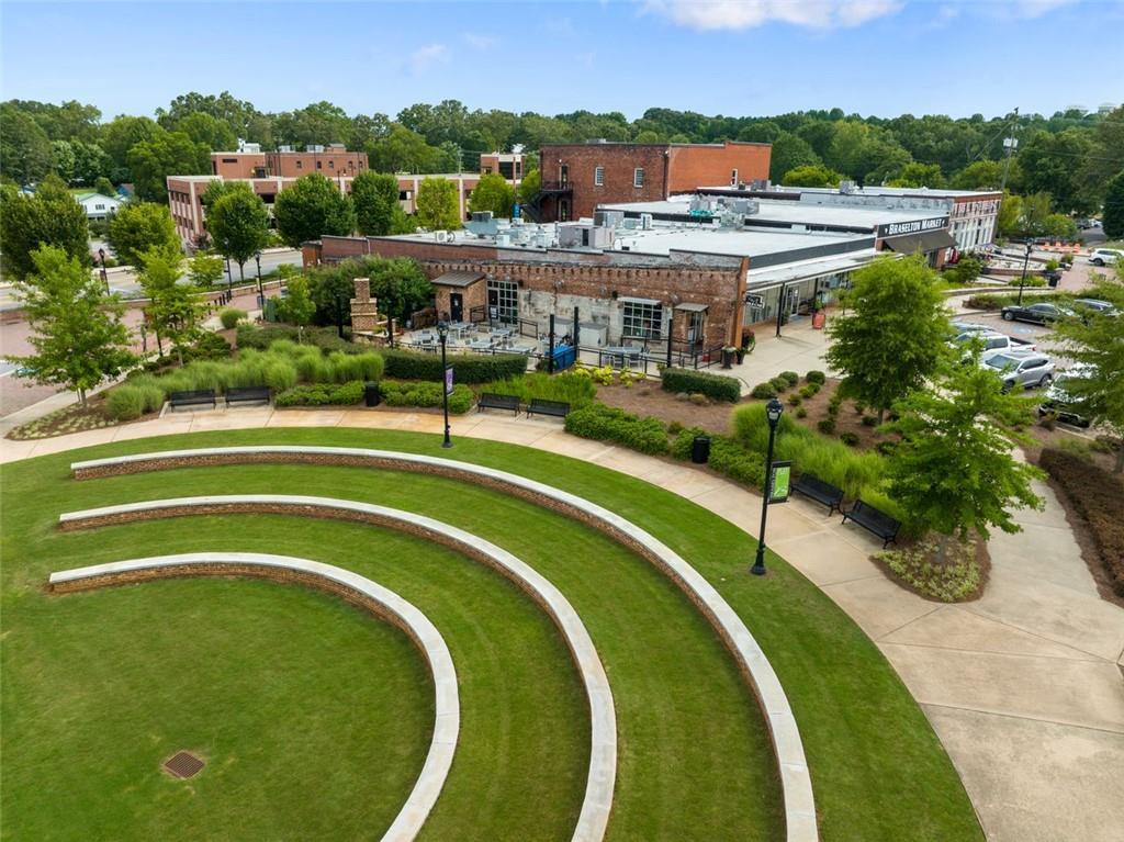 Aerial view of curved stone amphitheater in Wehunt Meadows plaza, Hoschton, Georgia, with brick buildings, lush greenery and pathways