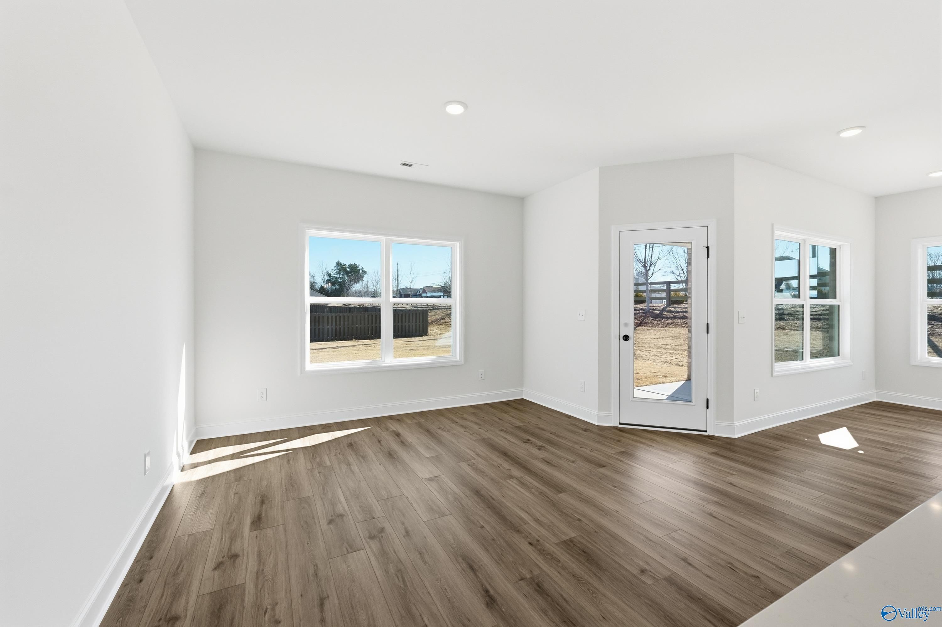 Bright living room with hardwood floors, large windows, and sliding glass doors to backyard in Davidson Homes The Franklin C, New Market, Alabama