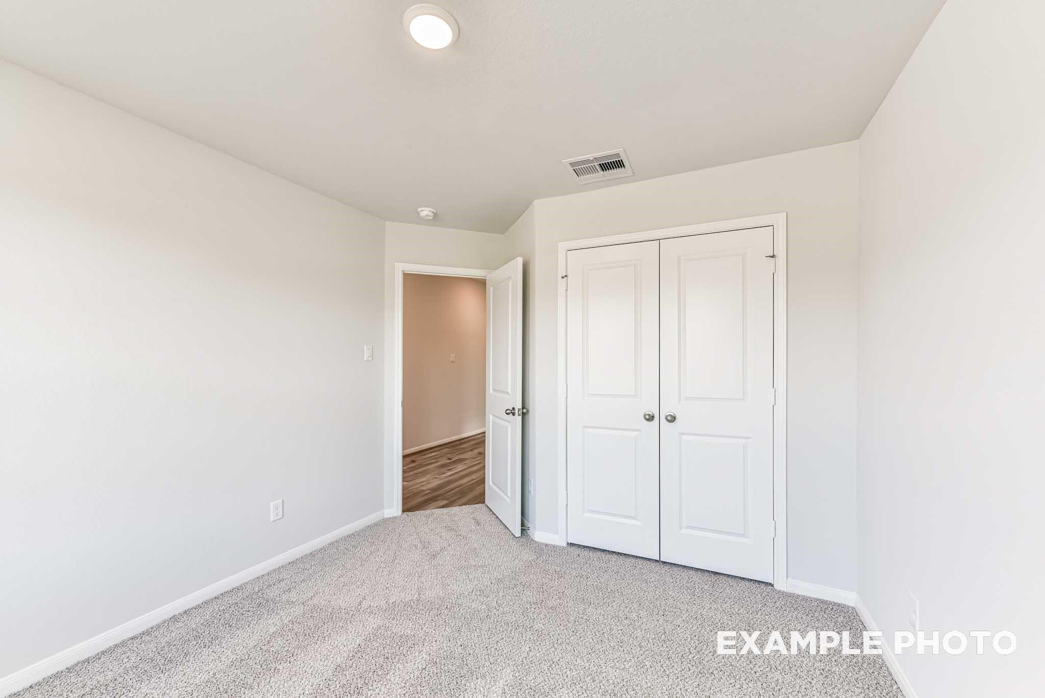 Bright secondary bedroom with carpet and double-door closet in The Laguna C floor plan by Davidson Homes in Sunterra, Katy.