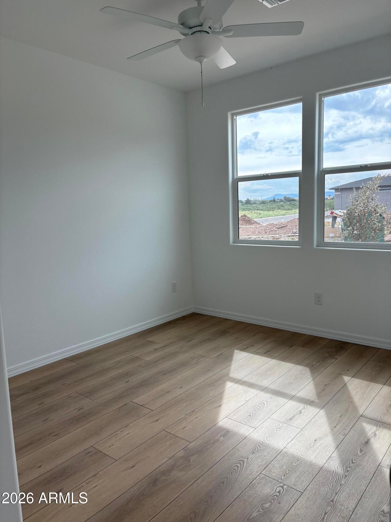 Bright bedroom with luxury vinyl plank flooring, ceiling fan, and double windows in Davidson Homes Evergreen B, Cottonwood, AZ
