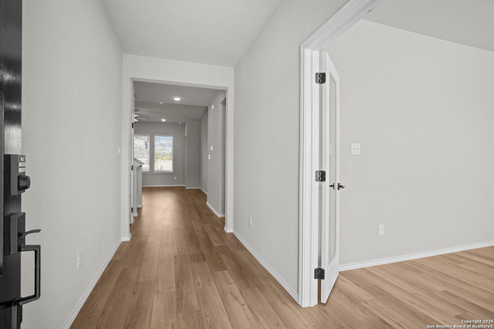 Bright hallway with hardwood floors, open doorways, and natural light in Davidson Homes The Sequoia A, Converse, Texas