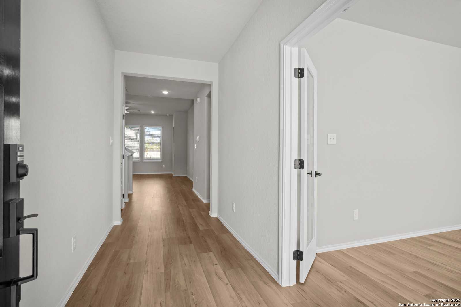 Bright hallway with hardwood floors, open doorways, and natural light in Davidson Homes The Sequoia A, Converse, Texas