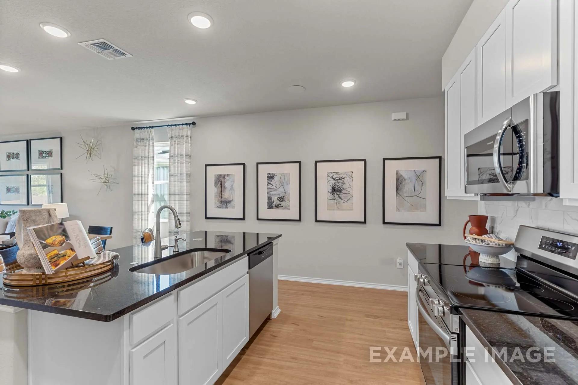 Modern kitchen with granite island and white cabinets in The Sabine H floor plan by Davidson Homes in Heartland, Texas.