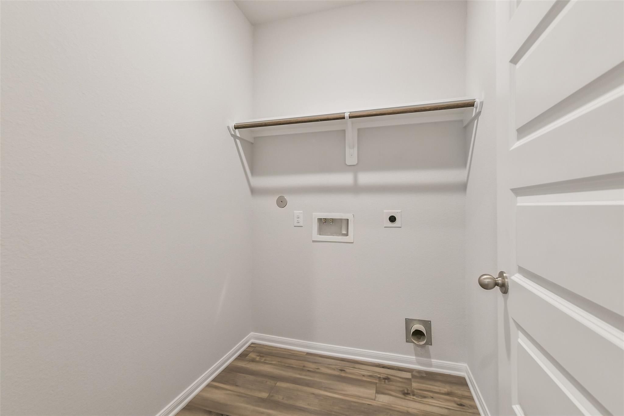 Spacious laundry room with washer/dryer hookups, built-in shelf and wood flooring in Davidson Homes The Brazos F, Conroe, Texas