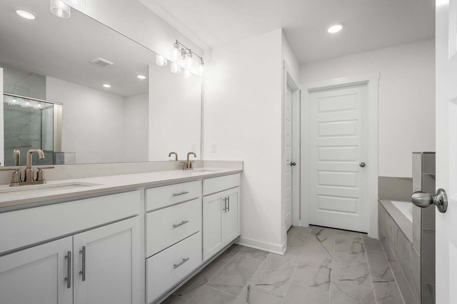 Modern primary bathroom with double vanity and tiled flooring in The Logan C floor plan at Calista Farms, White House, TN.